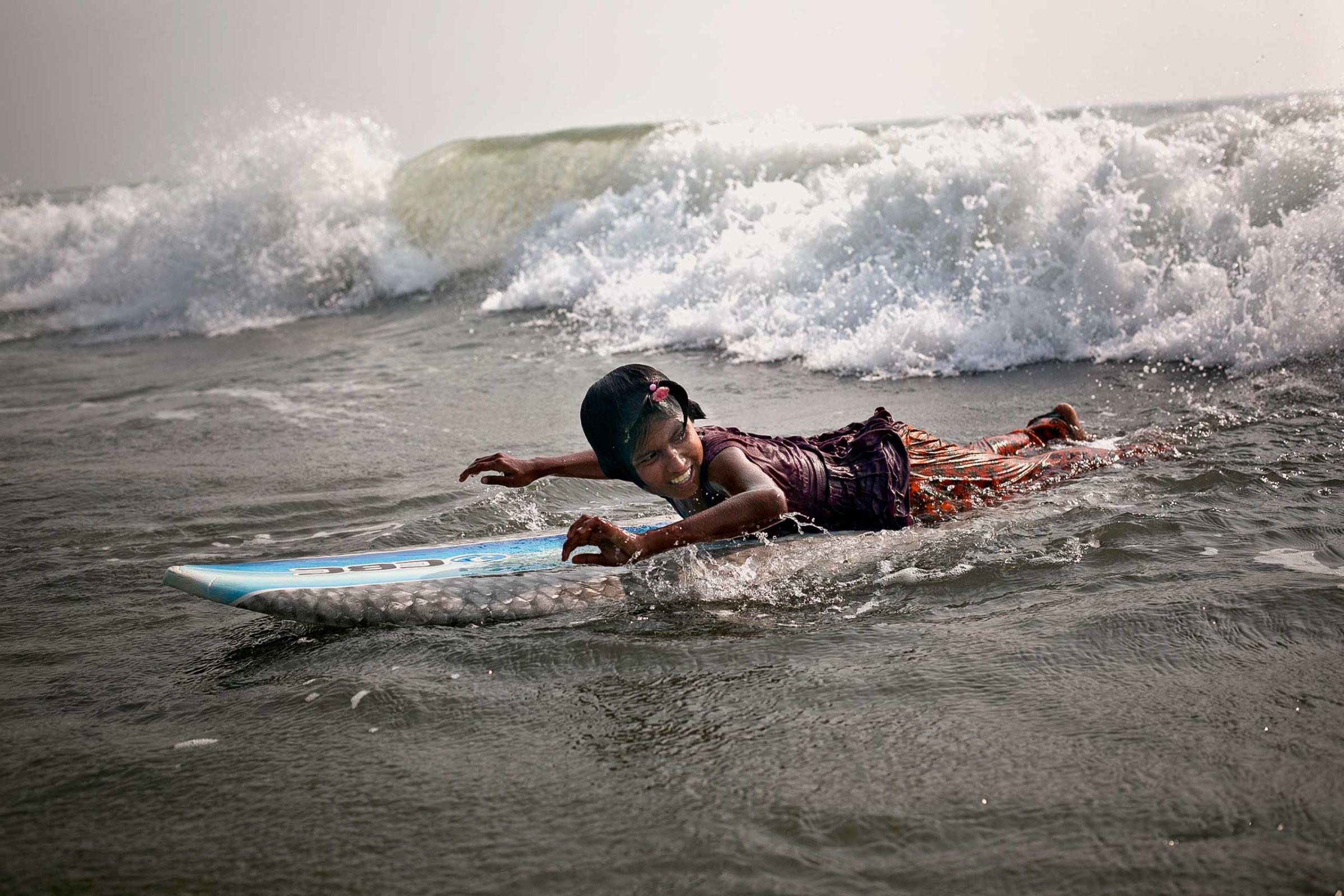 Ten-year-old Johanara surfs. The Bangladeshi surf girls are a group of eight outgoing and spunky girls ranging in ages 10 to 13 years old, who live and work in Cox's Bazar, Bangladesh. Poverty is forcing them into an early adulthood, as they are obligated to shoulder the responsibility of earning money to help feed their families. Early each morning, rain or shine, they leave their homes and make their way to the beach, where they work selling jewelry and eggs until late into the night before returning home. Their families are unable survive without the girls' income.