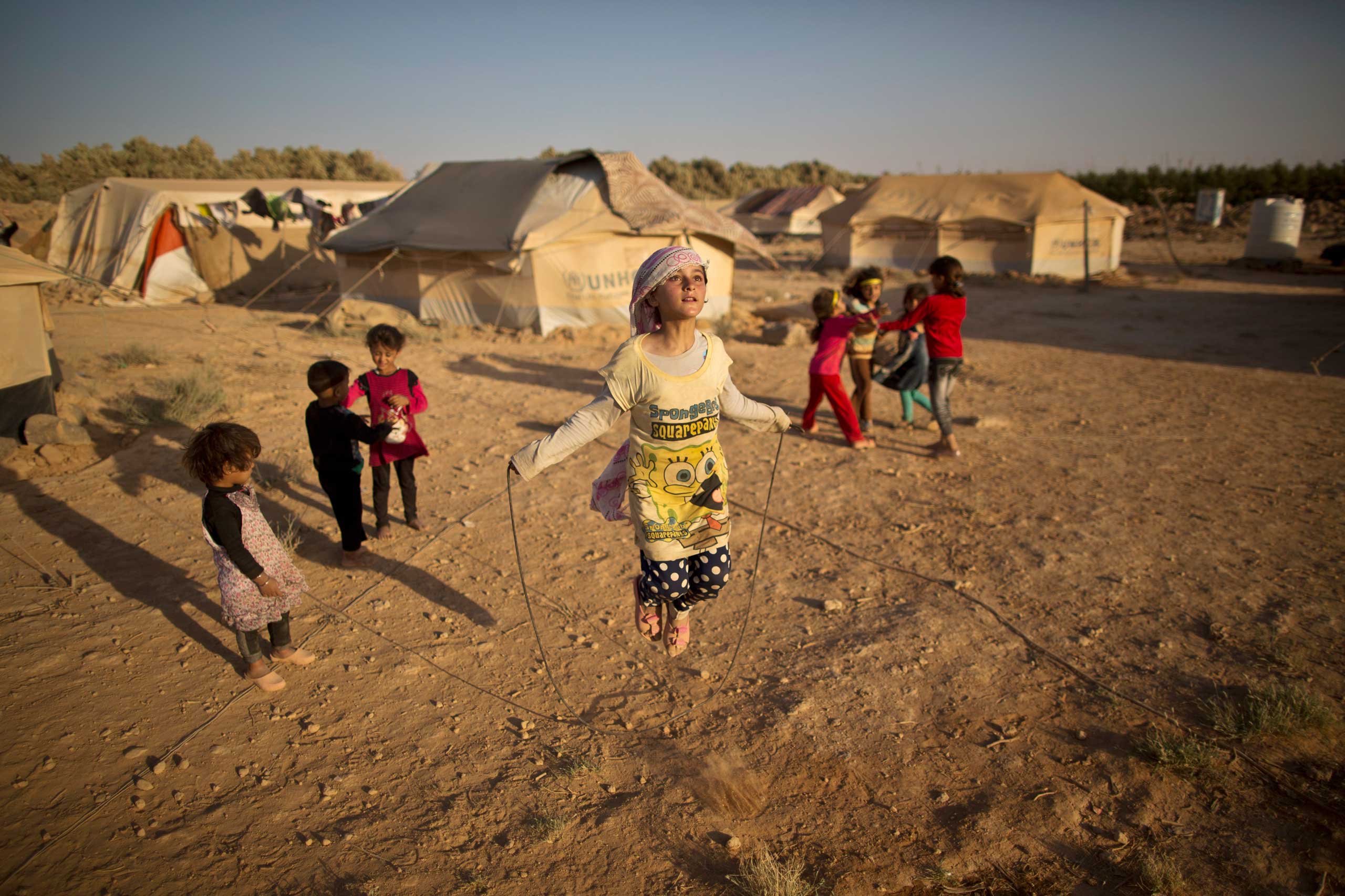 Syrian refugee girl, Zubaida Faisal, 10, skips a rope while she and other children play near their tents at an informal tented settlement near the Syrian border on the outskirts of Mafraq, Jordan. July 19, 2015.