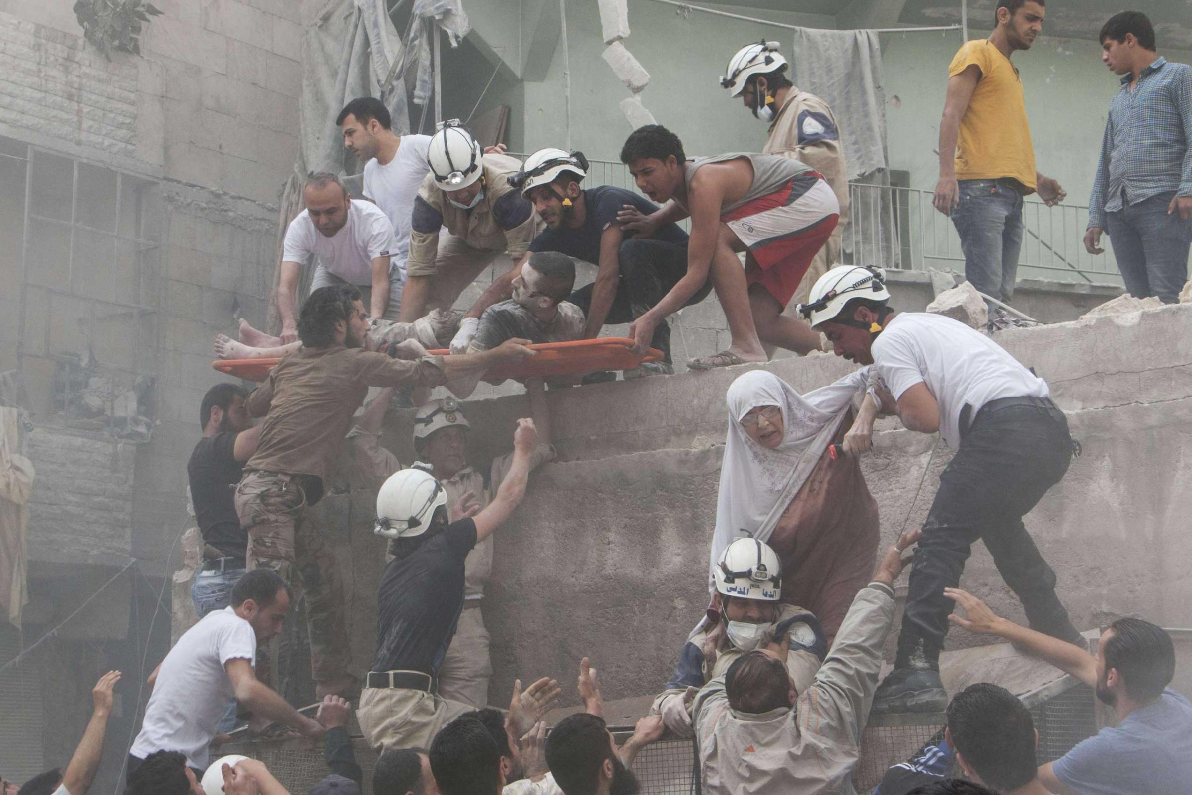 Syrian rescue workers and citizens evacuate people from a building following a reported barrel bomb attack by Syrian government forces on the central al-Fardous rebel-held neighborhood in the northern Syrian city of Aleppo. June 9, 2015