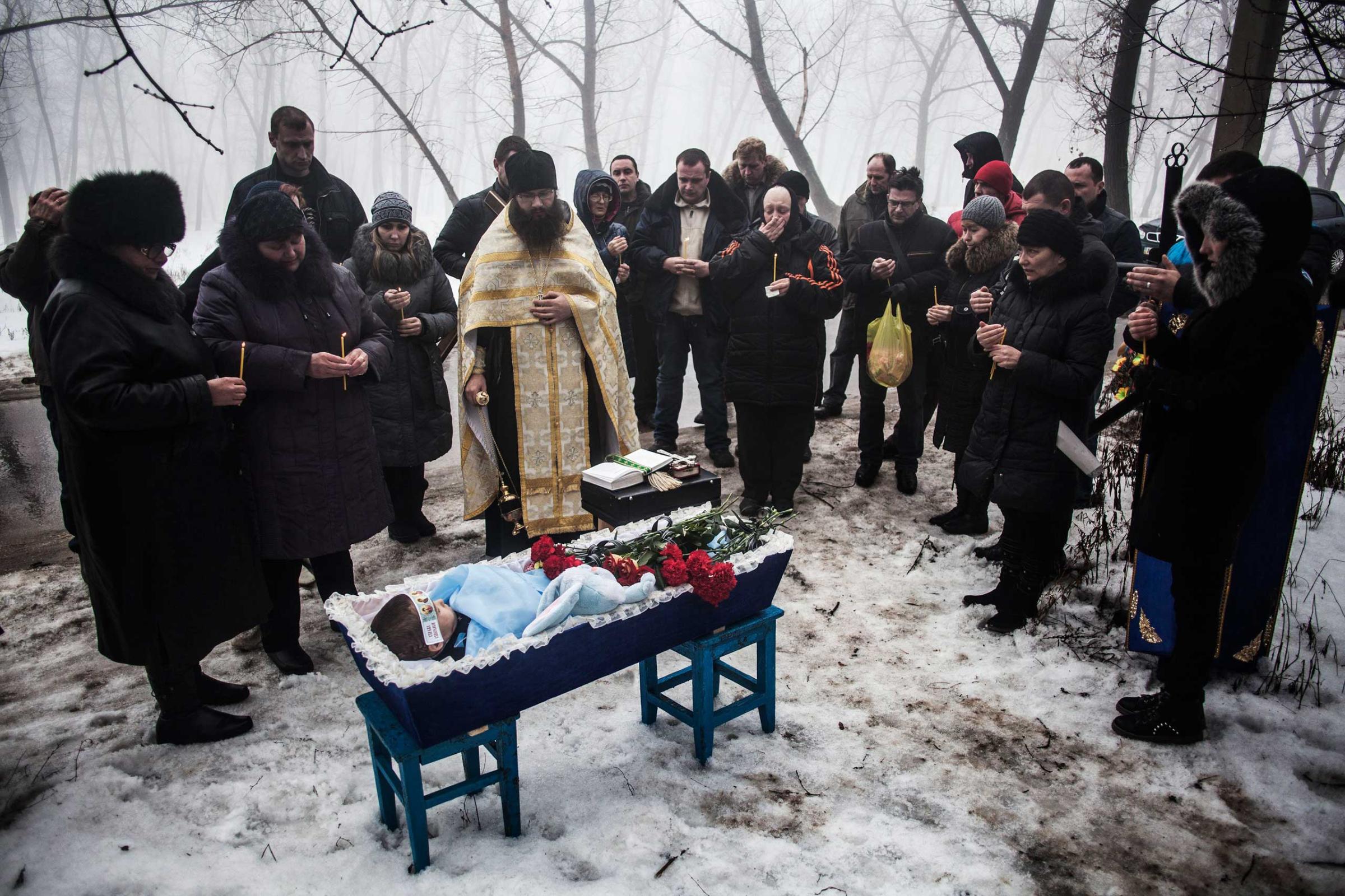 Mourners gather around a coffin bearing Artiam, 4, who was killed in a Ukrainian army artillery strike, during his funeral in Kuivisevsky district on the outskirts of Donetsk, eastern Ukraine. Jan. 20, 2015