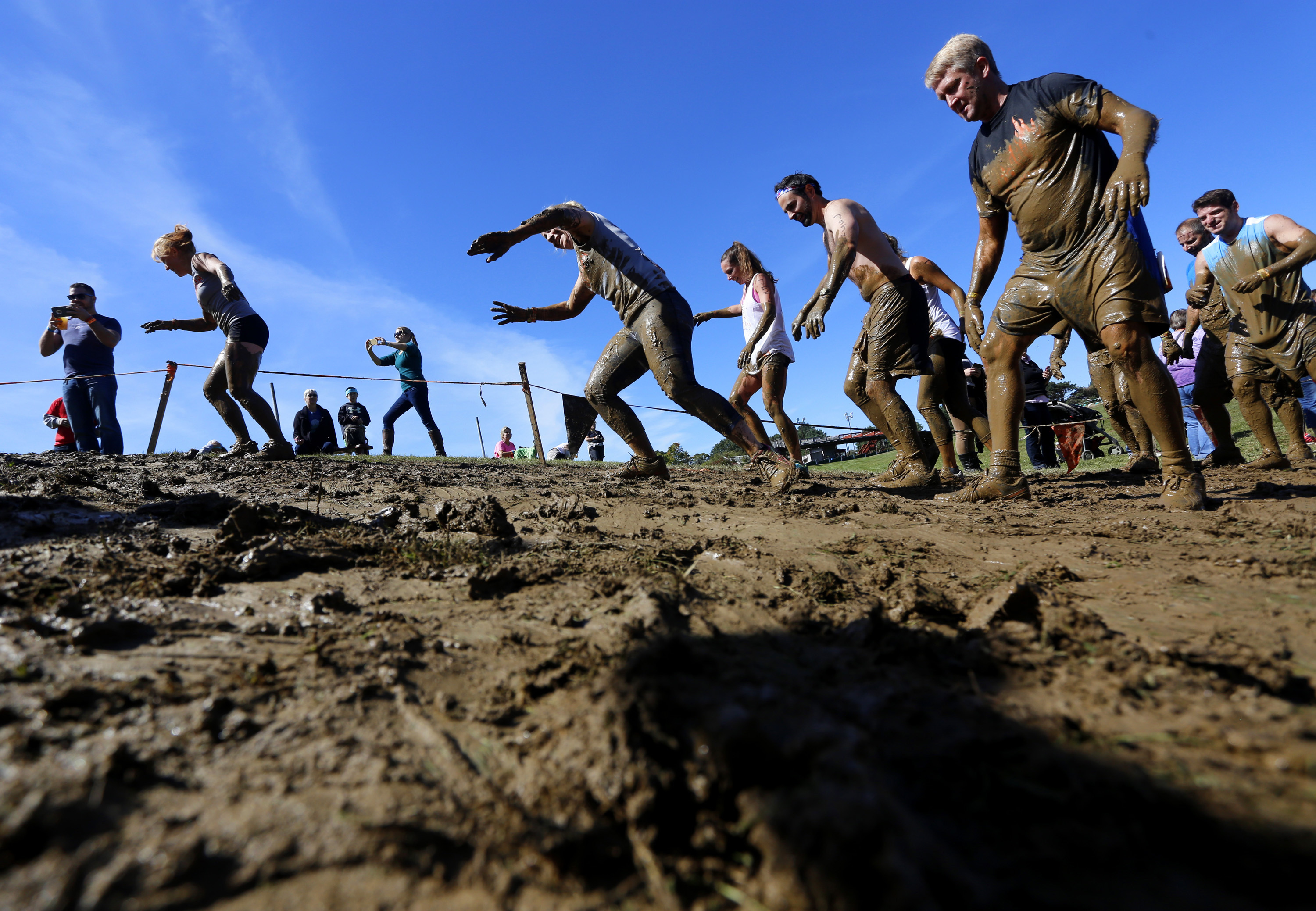 Participants climb a muddy hill after crawling through the "Kiss of Mud 2.0" obstacle during the Tough Mudder obstacle course on Sept. 26, 2015. (Derek Davis—Portland Press Herald/Getty Images)