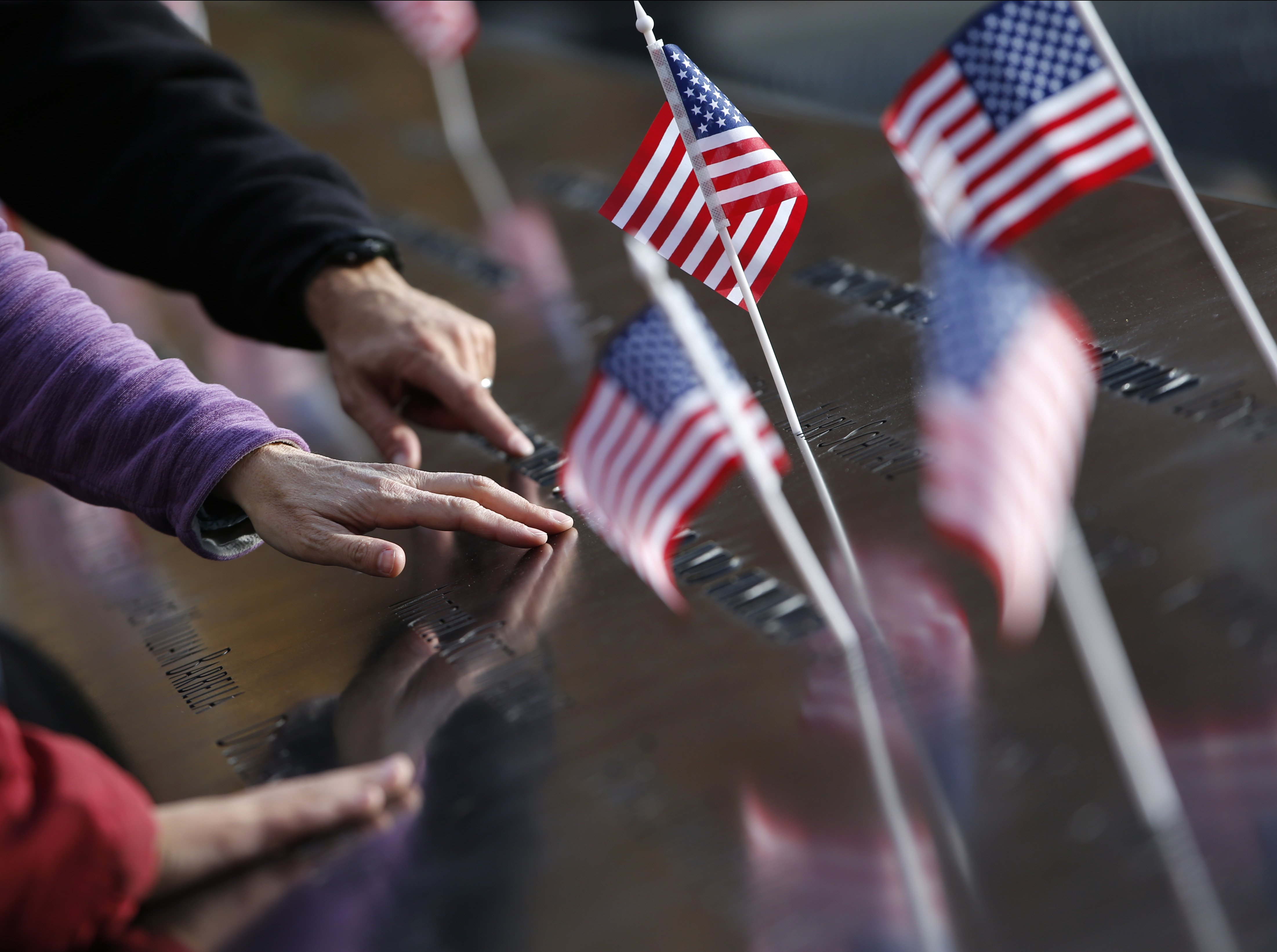 Hands reach out to touch the names inscribed at the South Pool of the 9/11 Memorial in New York City on Nov. 9, 2015. (Kathy Willens—AP)