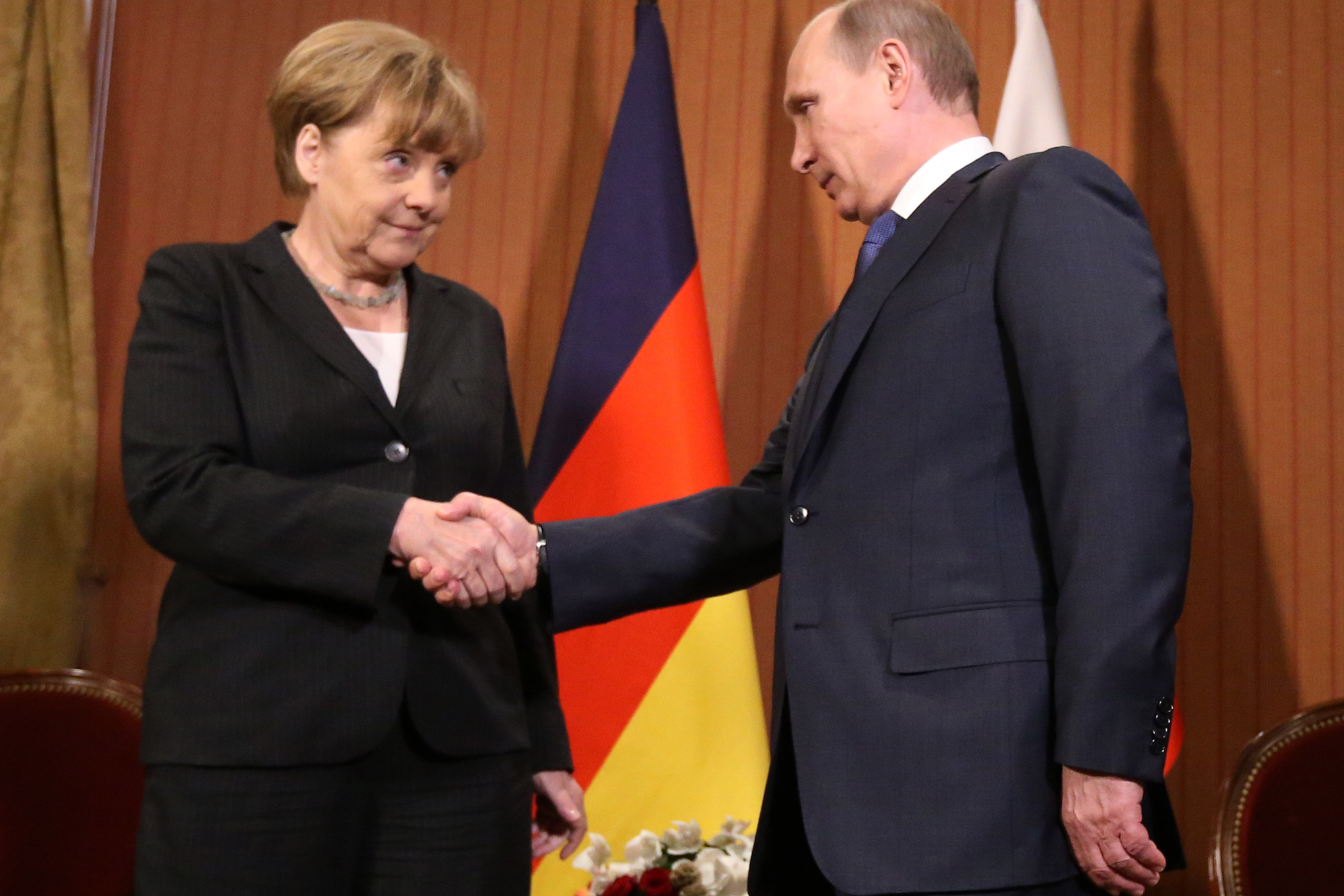 Russian President Vladimir Putin shakes hands with German Chancellor Angela Merkel of Germany during D-Day anniversary celebrations on June 6, 2014 in Deauville, France.