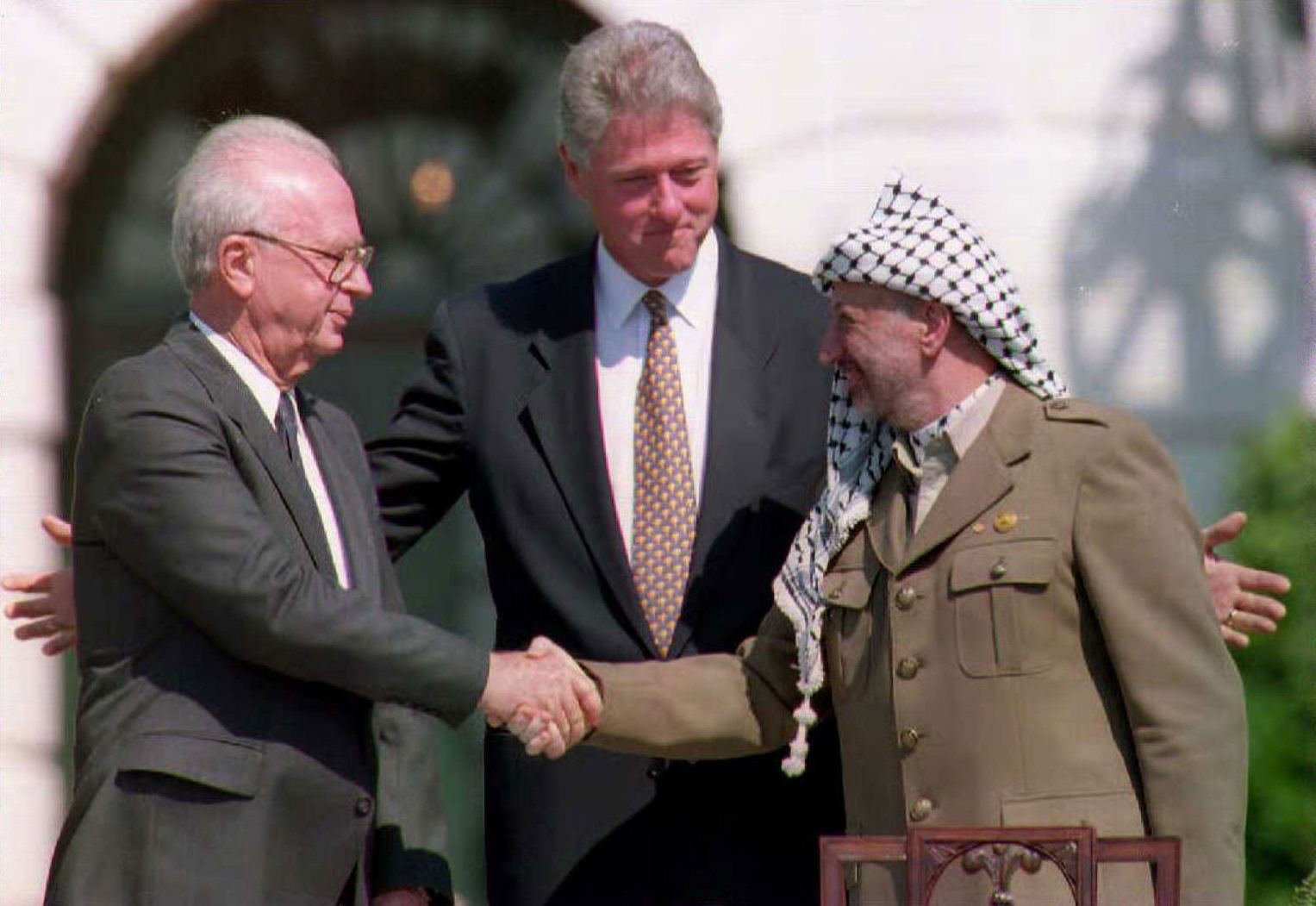 U.S. President Bill Clinton (C) stands between PLO leader Yasser Arafat (R) and Israeli Prime Minister Yitzahk Rabin (L) as they shake hands at the White House in Washington D.C. on Sept. 13, 1993.