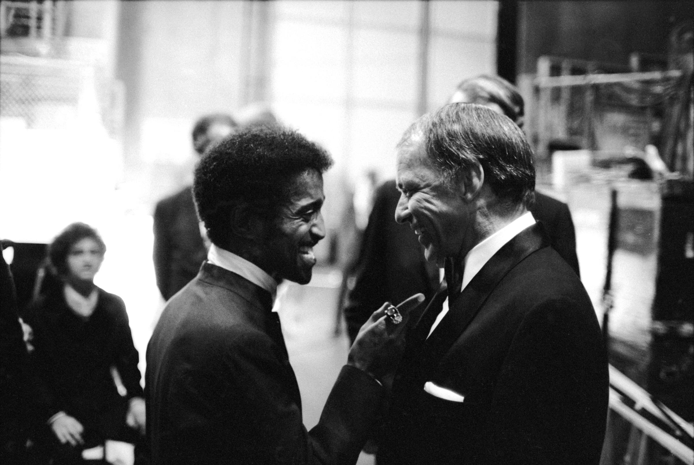 Sammy Davis Jr. talking with singer Frank Sinatra at his farewell peformance, at UCLA, 1971.