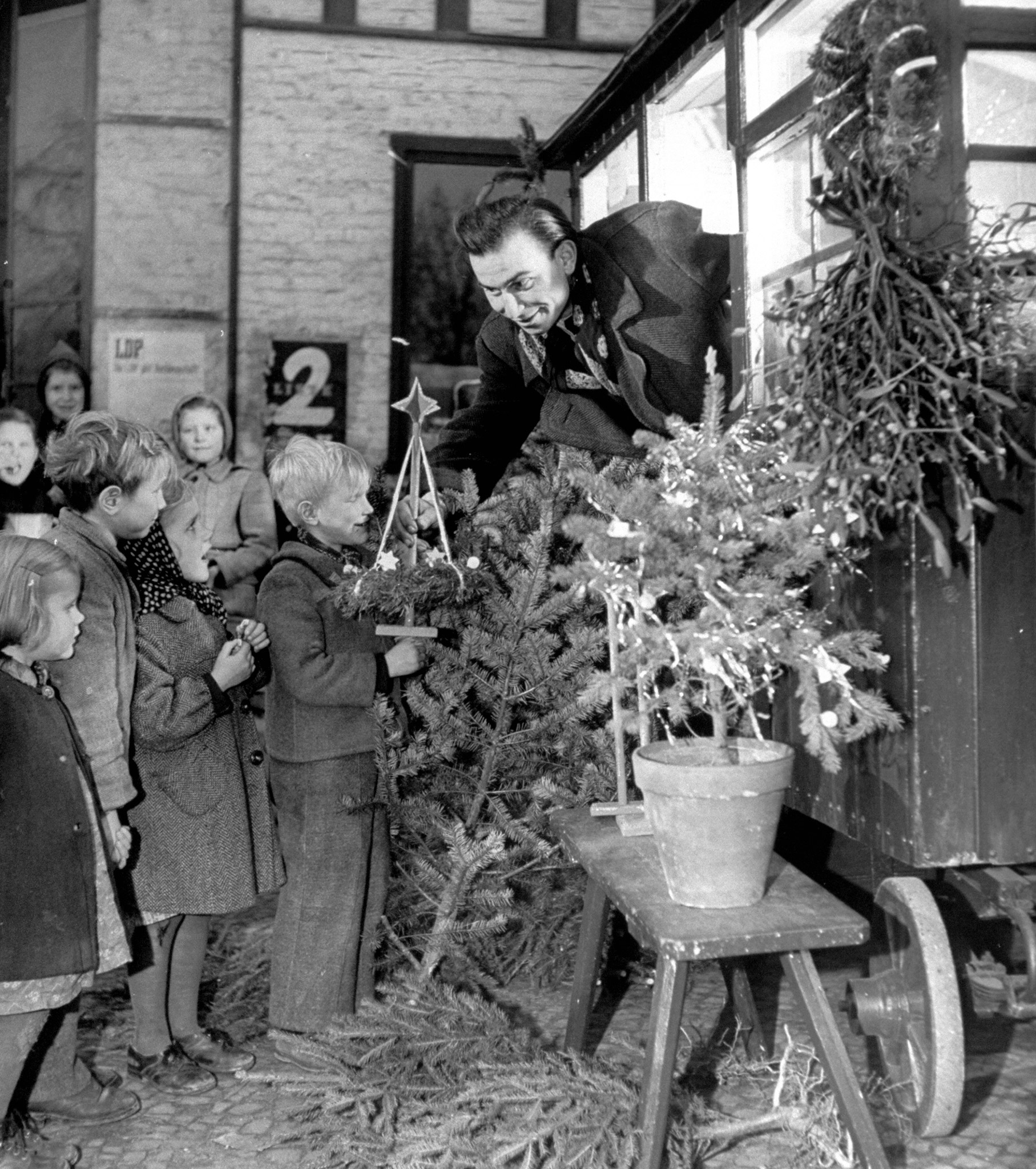 Man showing Christmas decorations to children, 1948.