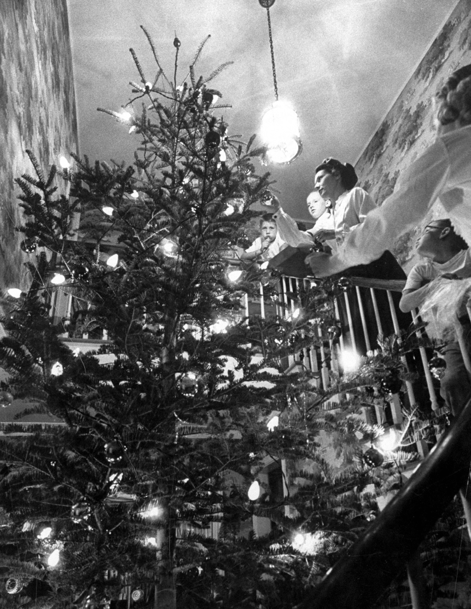 Mrs. George Sutton and her family decorating their Christmas tree at home, 1956.