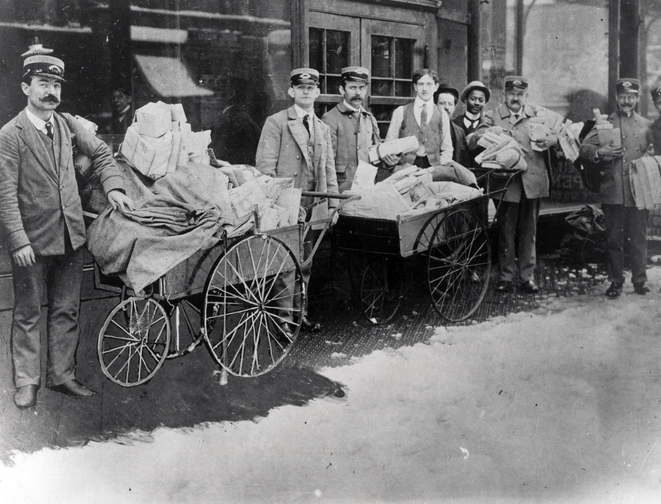 City letter carriers pose with handcarts used to collect and transport mail, 1885.