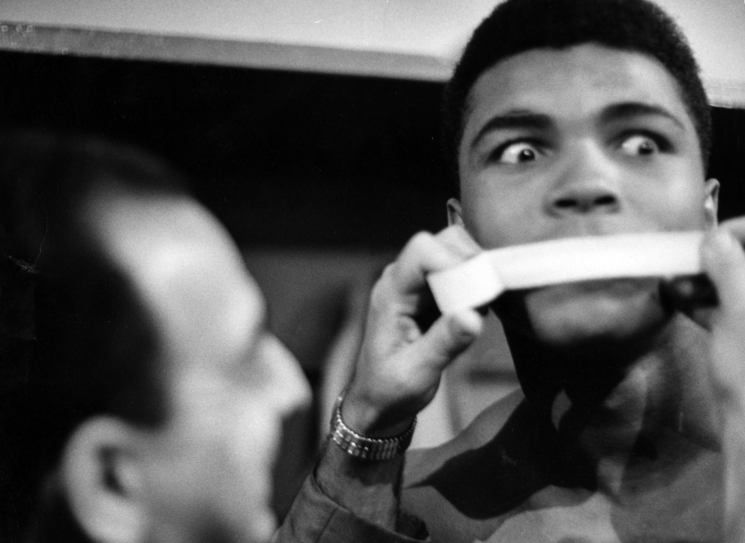 Heavyweight contender Cassius Clay (later aka Muhammad Ali), getting his poetic mouth taped by trainer Angelo Dundee during his weigh-in before big fight with Doug Jones, 1963.