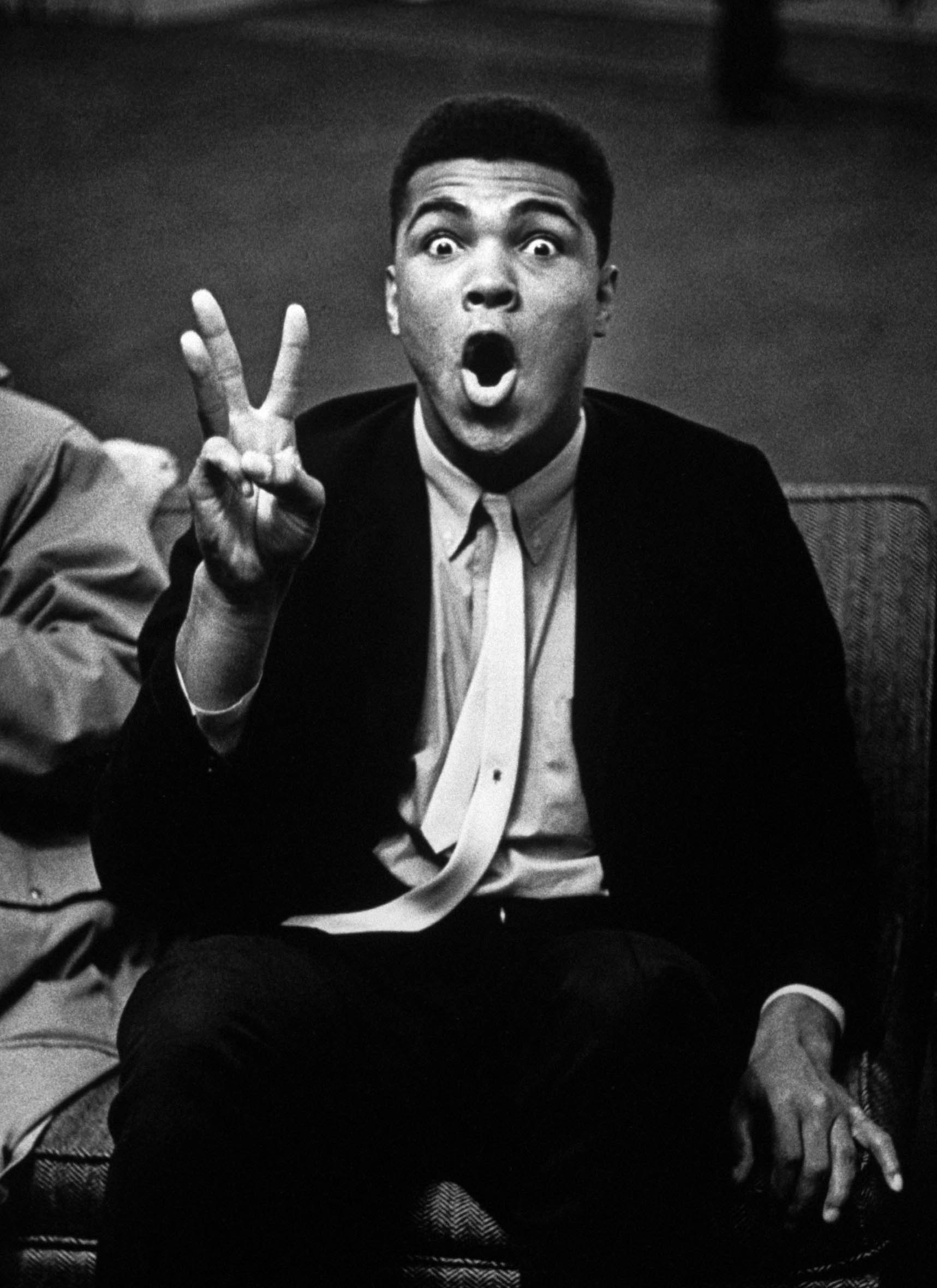 Boxing heavyweight contender Cassius Clay (later Muhammad Ali) holding up three fingers while reciting poem predicting that opponent Charlie Powell will fall in third round, 1963.