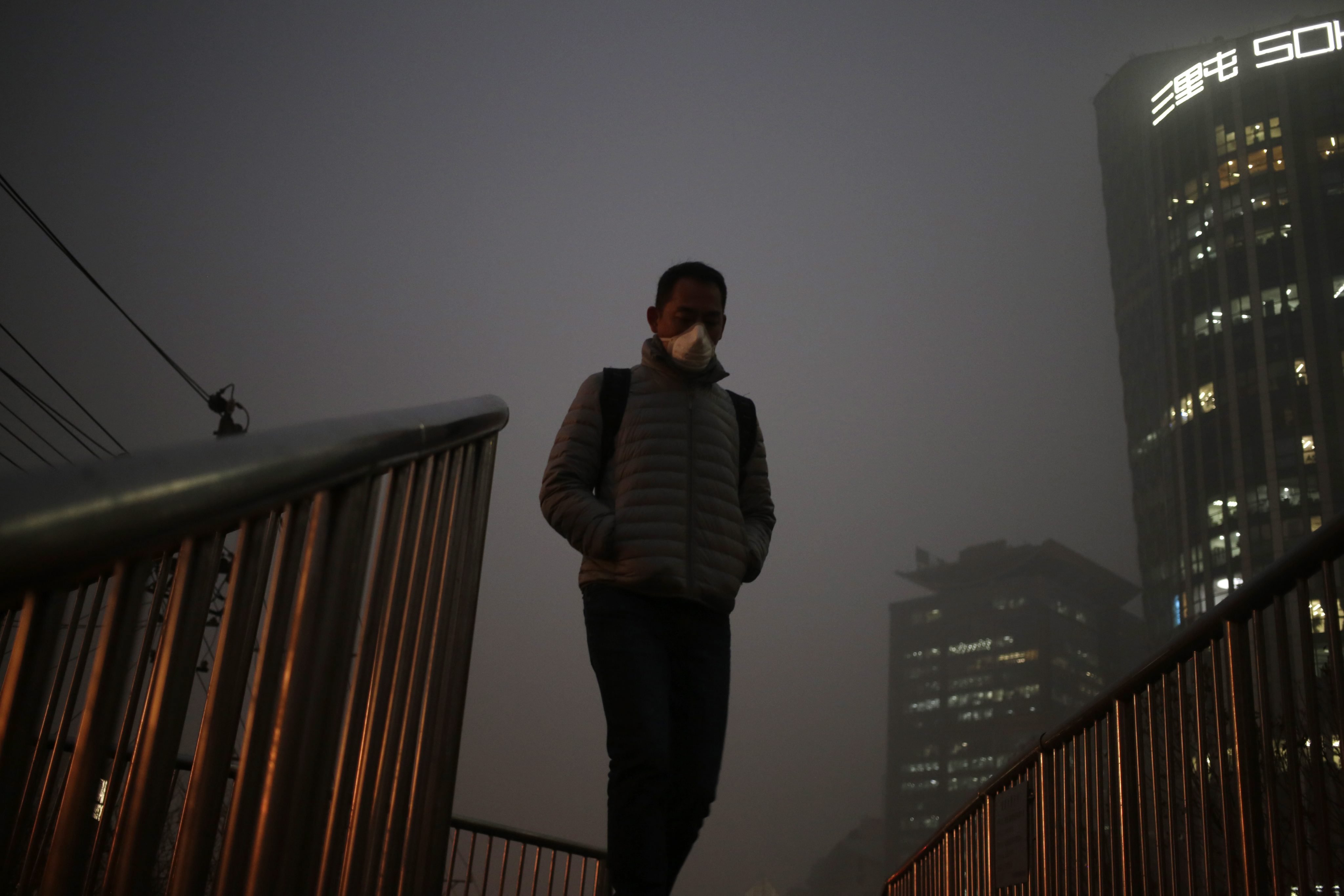 A man wears a mask as he walks on a bridge shrouded in smog in Beijing, Dec. 1, 2015. Beijing issued its second red alert for smog on Dec. 18, 2015, urging schools to close and residents to stay indoors for the second time in 10 days. (How Hwee Young—EPA)