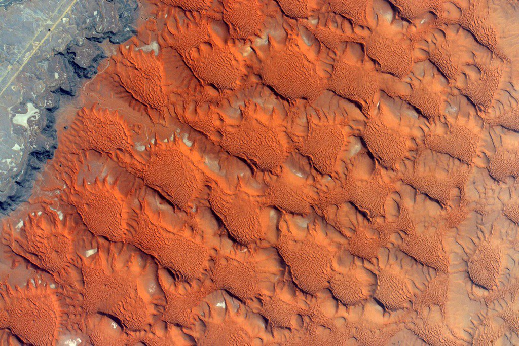 The stark transition between radiating sand dunes and an old volcanic flow on the surface of Earth was captured by astronaut Kjell Lindgren aboard the International Space Station, on Dec. 5 2015.