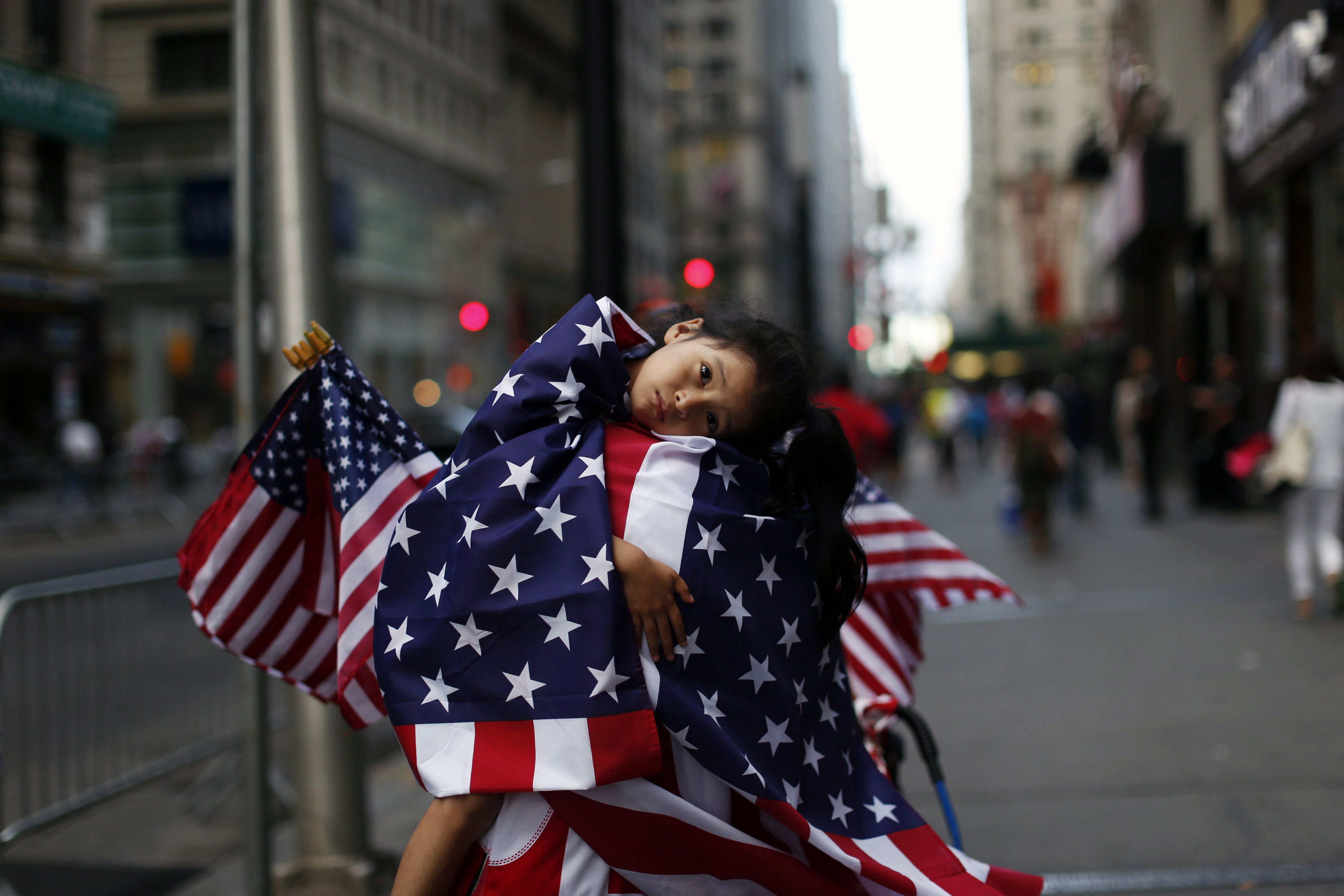 A child draped in United States flags rests on a revelers' shoulder ahead of a ticker-tape parade celebrating the World Cup victory for the U.S. women's soccer team in New York on July 10, 2015.