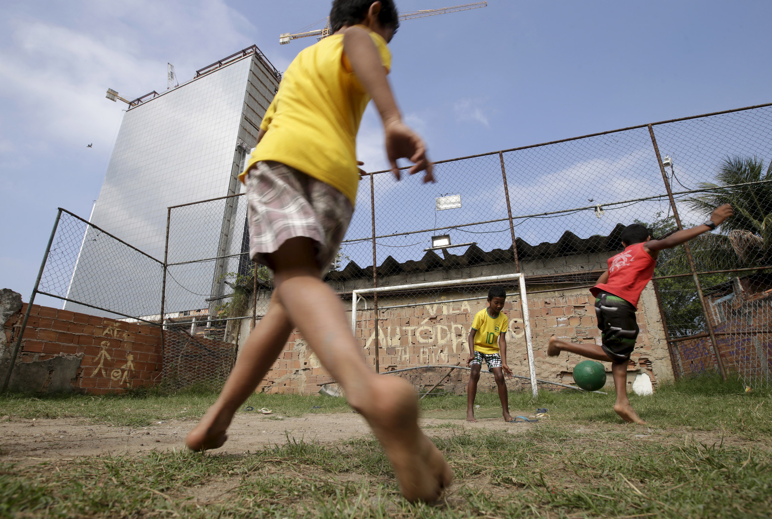 Children play soccer in the Vila Autodromo slum in Rio de Janeiro, Brazil, July 28, 2015. As sports arenas rise up around them and neighbours' houses are demolished, around 50 families remain in Vila Autodromo, a favela bordering the Olympic Park in Rio de Janeiro. About half of those refuse to leave the favela, which they describe as "paradise" because of a lack of violence compared with poor areas elsewhere in the city. With a year until the Games come to Brazil, over 90 percent of residents have already left after accepting compensation. The holdouts, despite violent run-ins with police, vow to fight eviction whatever the cost. Living in a ghost town with sporadic access to water and electricity, the families have become a symbol against the use of the Olympic Games to modernize Rio, a move critics say is only benefiting the rich. REUTERS/Ricardo Moraes TPX IMAGES OF THE DAYPICTURE 6 OF 28 FOR WIDER IMAGE STORY "FIGHTING OLYMPIC EVICTION IN RIO FAVELA" SEARCH "RICARDO PARADISE" FOR ALL IMAGES ‚Ä®      TPX IMAGES OF THE DAY      - RTX1Q0DR