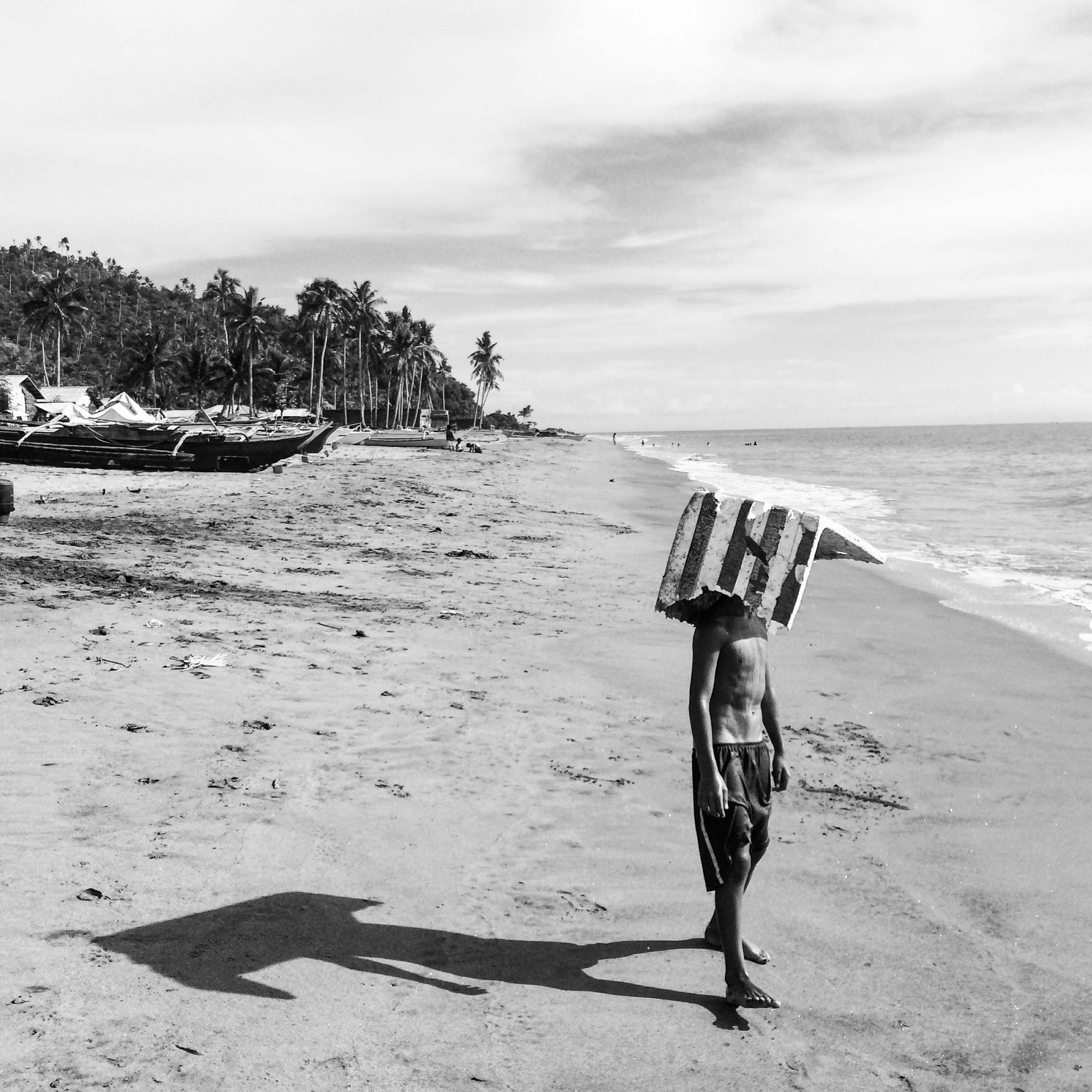 A child takes shelter from the heat with a cardboard panel along the coast of Tanauan on Oct, 7, 2015.