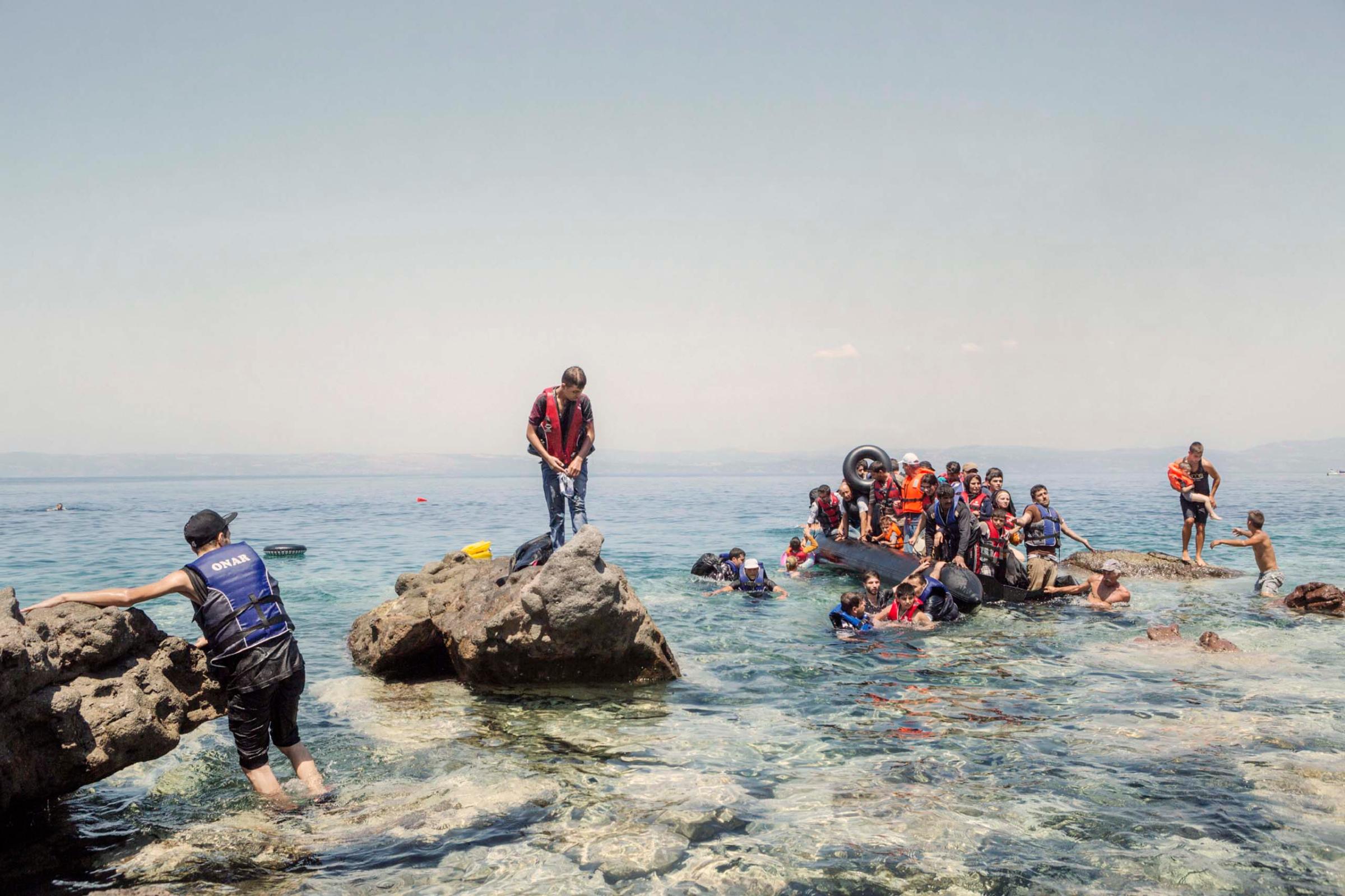 A boat carrying Syrians and people of other nationalities is dragged ashore by two local farmers. The boat had started to leak, forcing a small group of people to swim to the beach in Lesbos, Greece, Aug. 5, 2015.