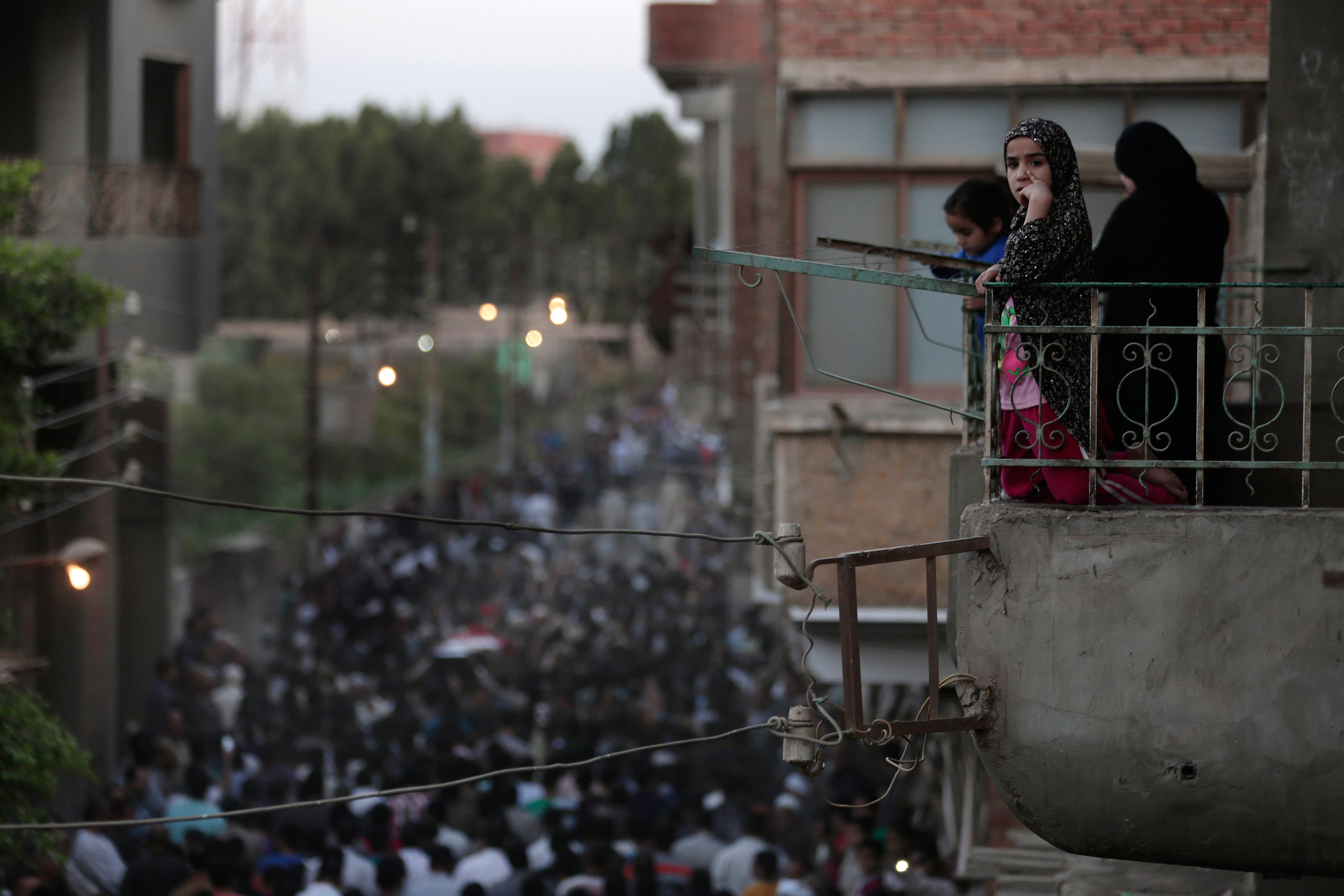 Egyptians mourn as they watch from their balcony during the funeral procession of 1st Lt. Mohammed Adel Abdel Azeem, killed in Wednesday's attack by Islamic militants in the Sinai, at his home village Tant Al Jazeera in Qalubiyah, north of Cairo, Egypt, Thursday, July 2, 2015. Islamic State-linked militants launched an unprecedented wave of attacks in northern Sinai on Wednesday, setting off the fiercest fighting the peninsula has seen in decades and undermining government efforts to stem the insurgency. (AP Photo/Hassan Ammar)