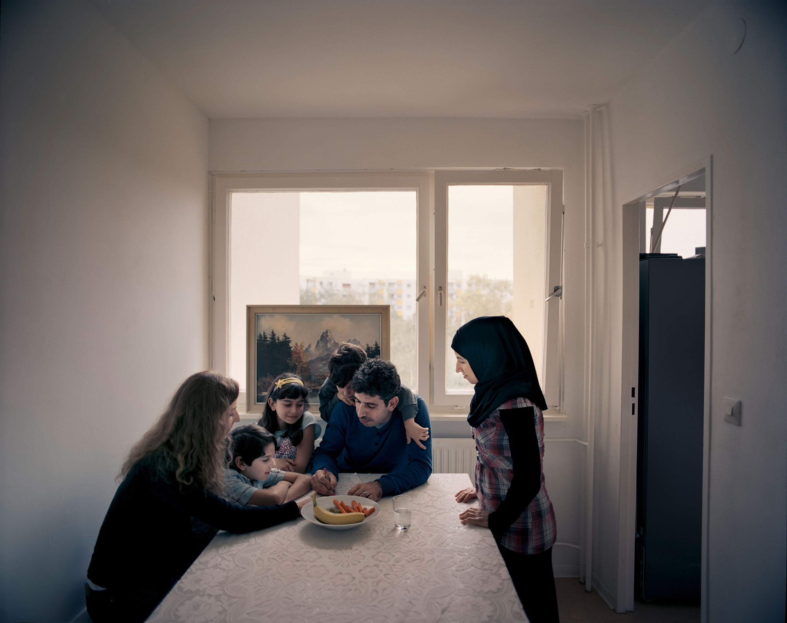 Britta Leben, left, a 27-year-old German master’s student, helps Zakaria Edelbi, 30, center, with his German-­language work. Edelbi came to Berlin in August 2014, leaving behind his wife and three children in Aleppo. He was reunited with them in March 2015 after months of trying to secure visas. Leben first met Edelbi in May, thanks to Beginn Nebenan Berlin, an organization that connects locals with refugees. “I just wanted to get to know the people we’re sharing this city with,” she says. “And Zakaria’s family is so open-­minded and fun to be around.” In late August, the Edelbis moved out of a shelter and into their own flat in Spandau, West Berlin. The children now attend school nearby and already speak some German. Edelbi says he fears for Syria’s ­future—but for the first time, he is no longer afraid for his children.From   The Welcome.  October 19, 2015 issue.