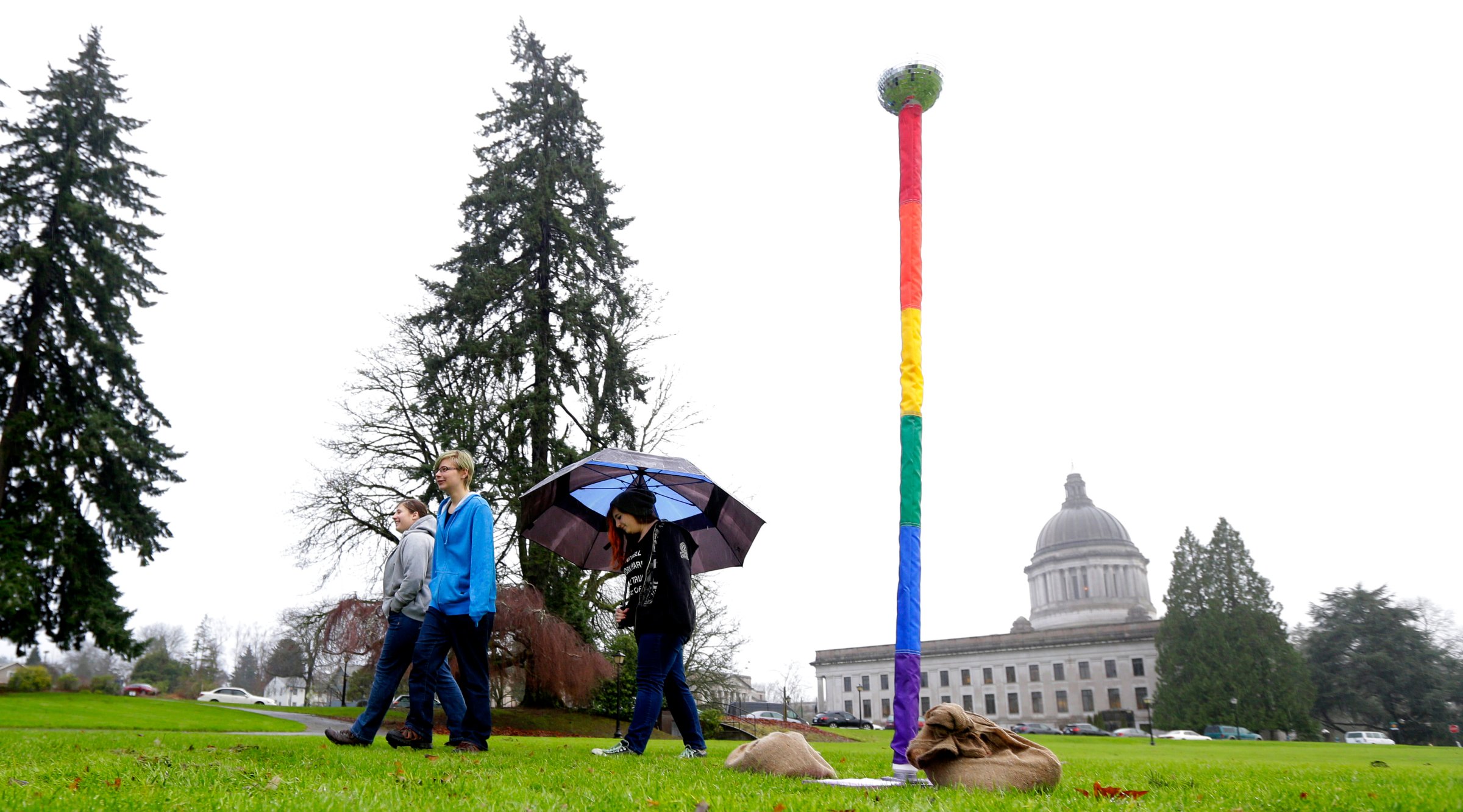 From left, siblings Kelli, Caitlynn, and Kerri Ray walk near a "Festivus Pole" supporting gay rights that they helped their father, Robert Ray, put up on Dec. 21, 2015, at the Capitol in Olympia, Wash.