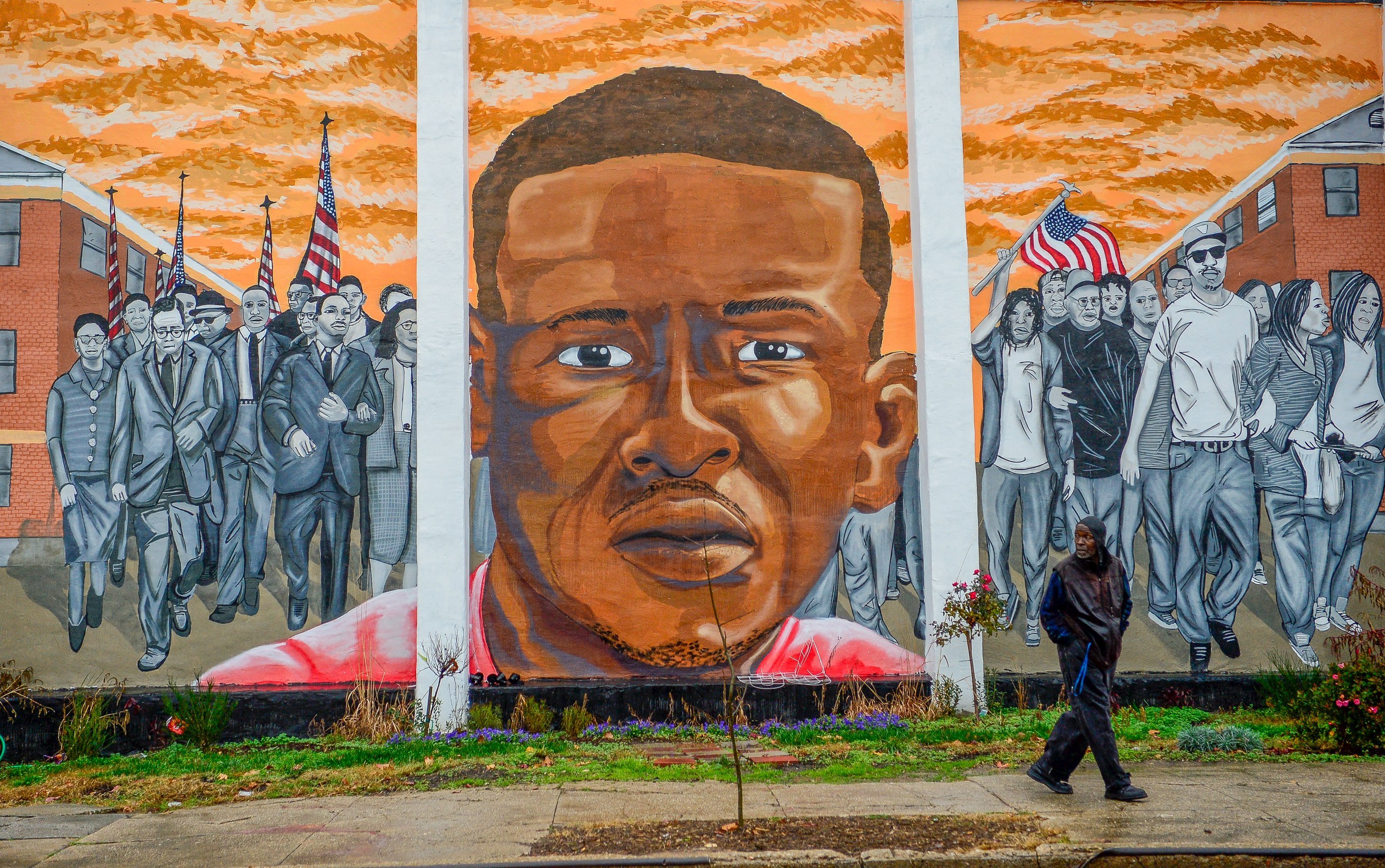 A man, who declined to offer his name, walks past a mural of Freddie Gray in the Sandtown-Winchester neighborhood of Baltimore