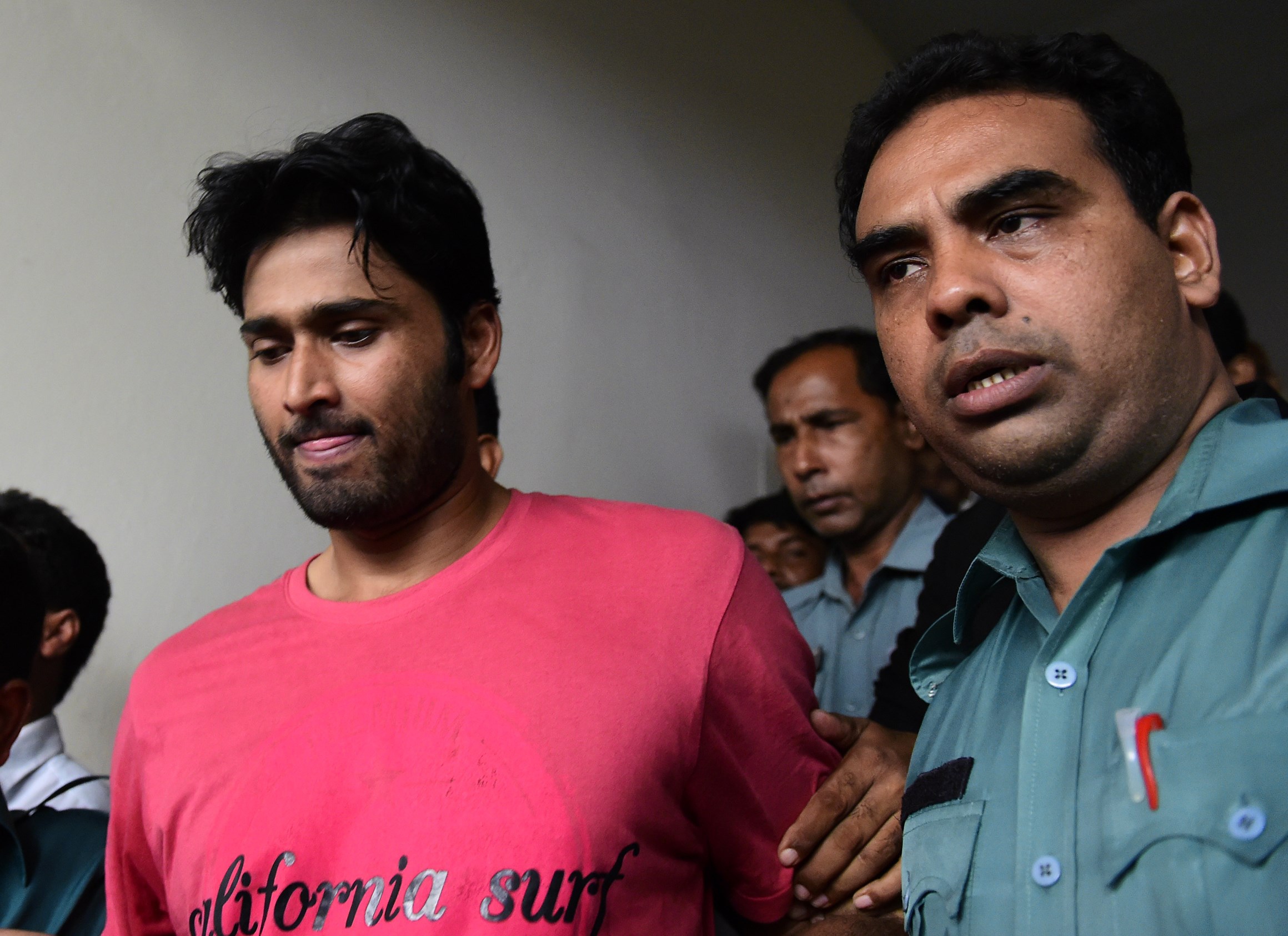 Bangladeshi security personnel escort fugitive cricketer Shahadat Hossain, center, after he surrendered in Dhaka on Oct. 5, 2015 (Munir Uz Zaman—AFP/Getty Images)