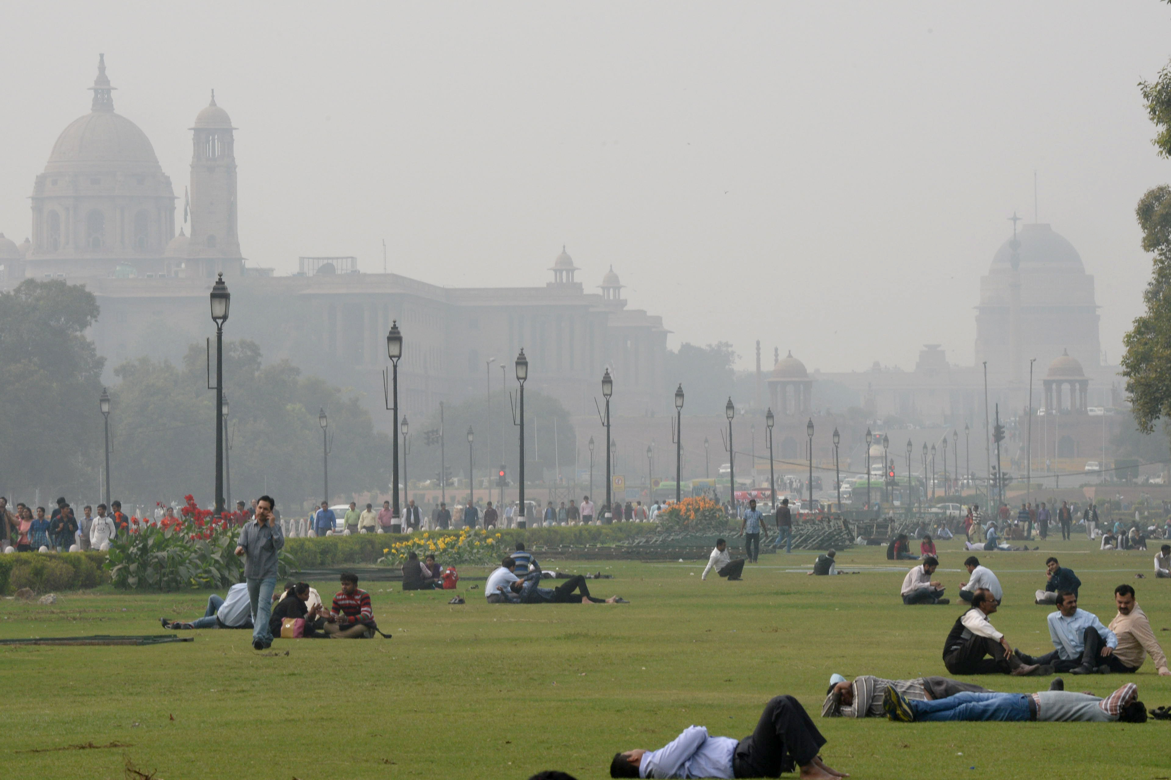 Indian people relax on the lawns near smog enveloped government offices on Rajpath in New Delhi on December 2, 2015. (PRAKASH SINGH—AFP/Getty Images)