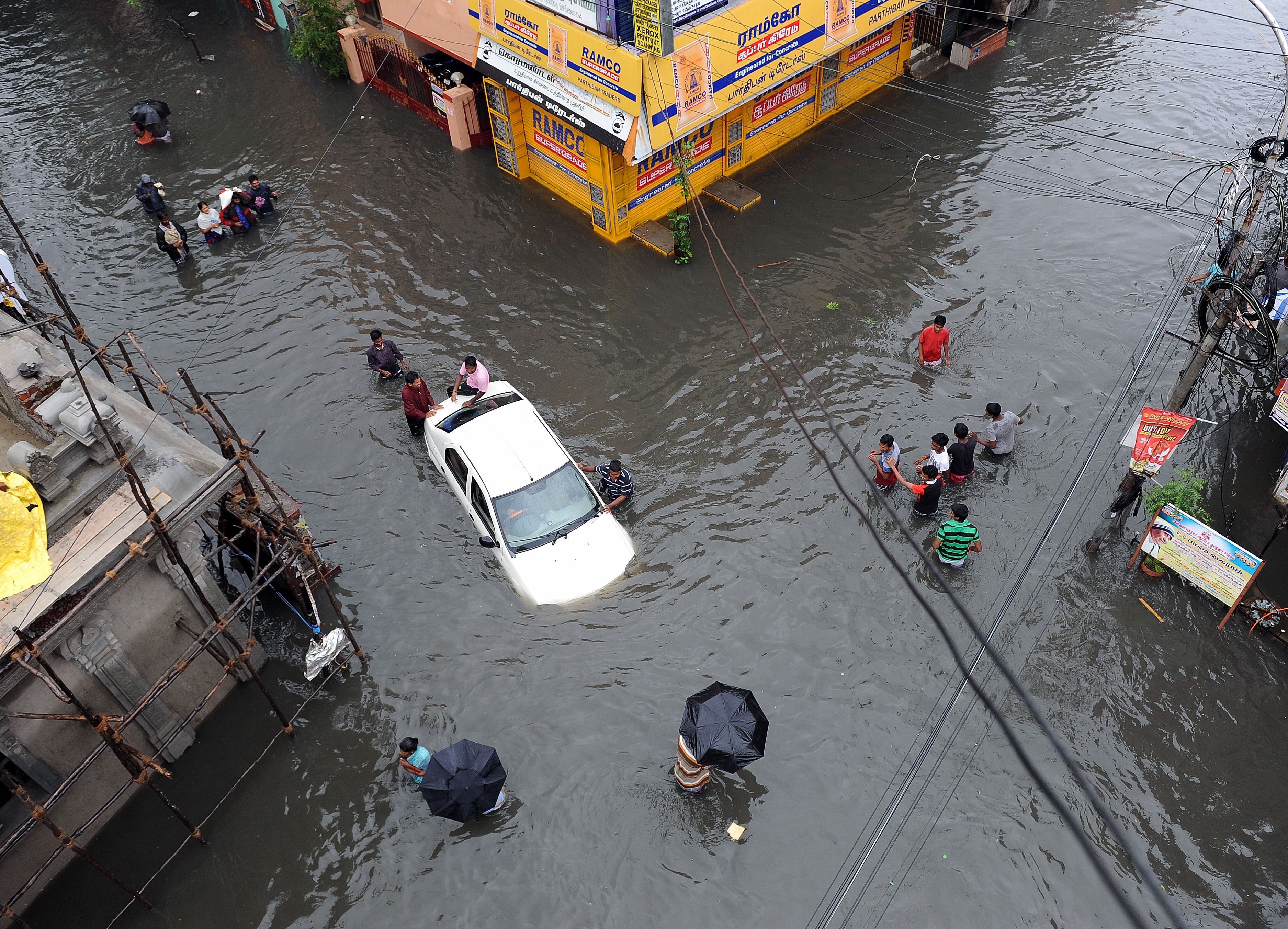 Indian residents attempt to push a vehicle through floodwaters as others wade past in Chennai on Dec. 2, 2015 (STRDEL—AFP/Getty Images)
