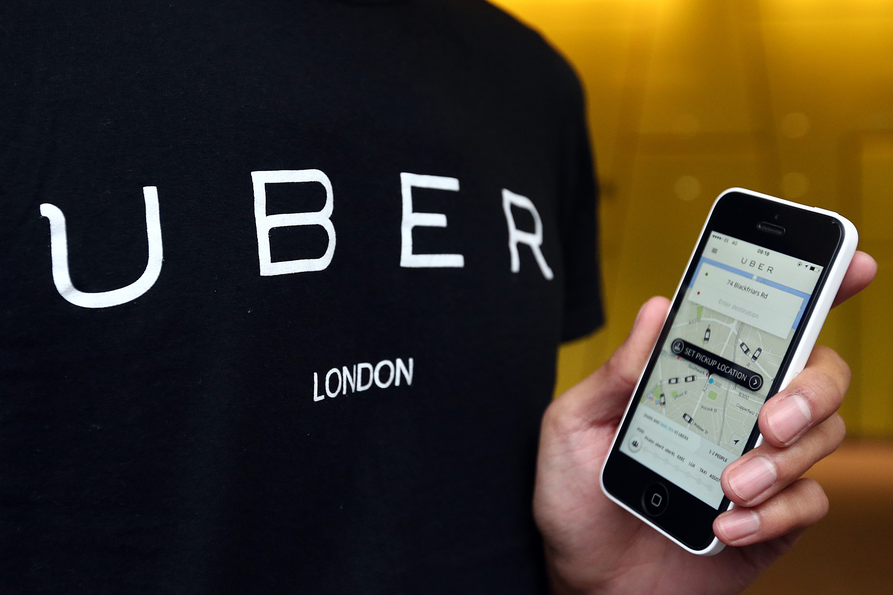 An Uber driver poses for a photograph in an Uber t-shirt and holding a smart phone displaying the Uber app after delivering petitions to the Transport for London headquarters on December 22, 2015 in London, England. (Carl Court&mdash;Getty Images)