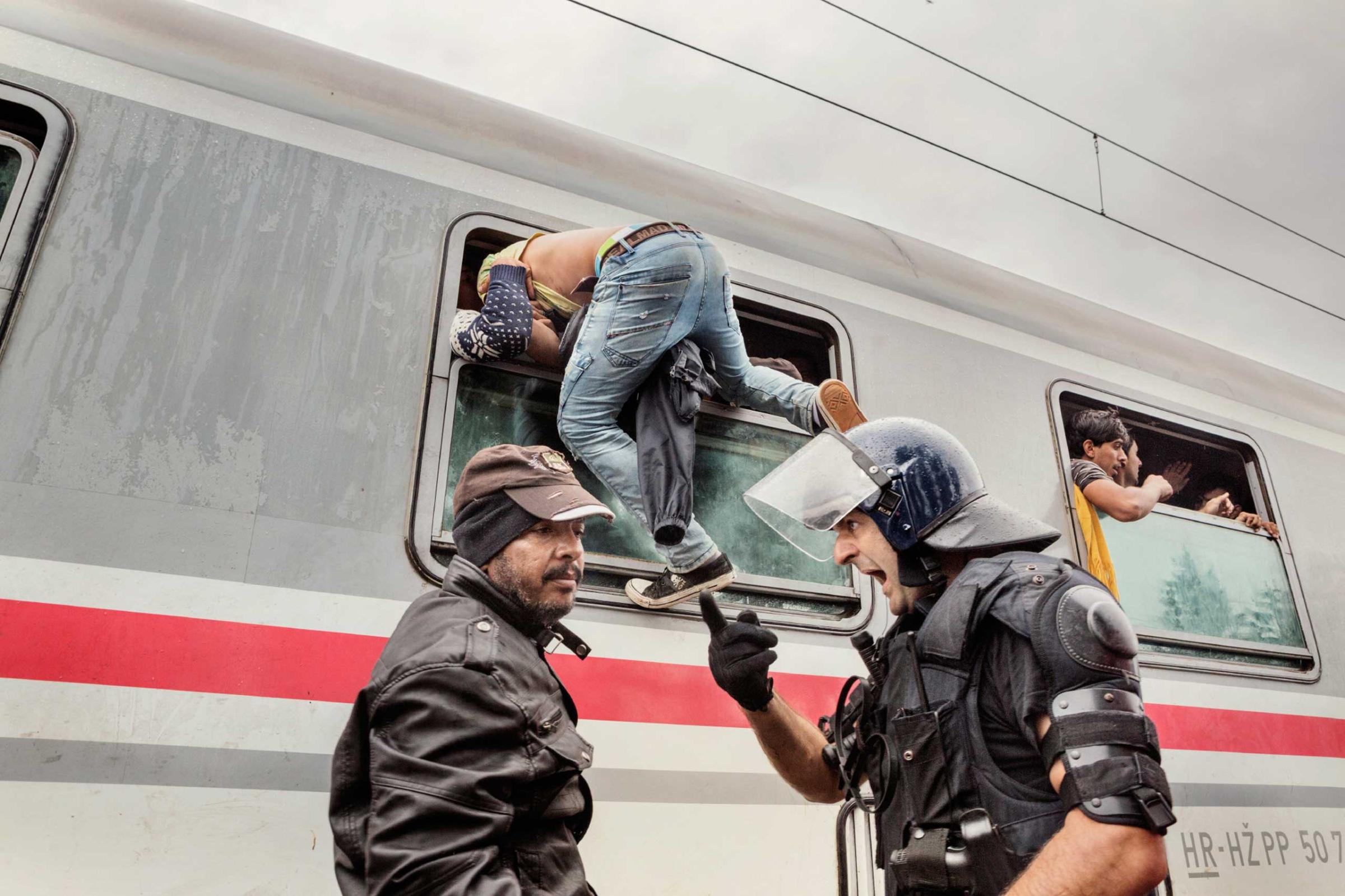 A police officer screams at a man as he attempts to board a train in Tovarnik, Croatia, Sept. 20, 2015.