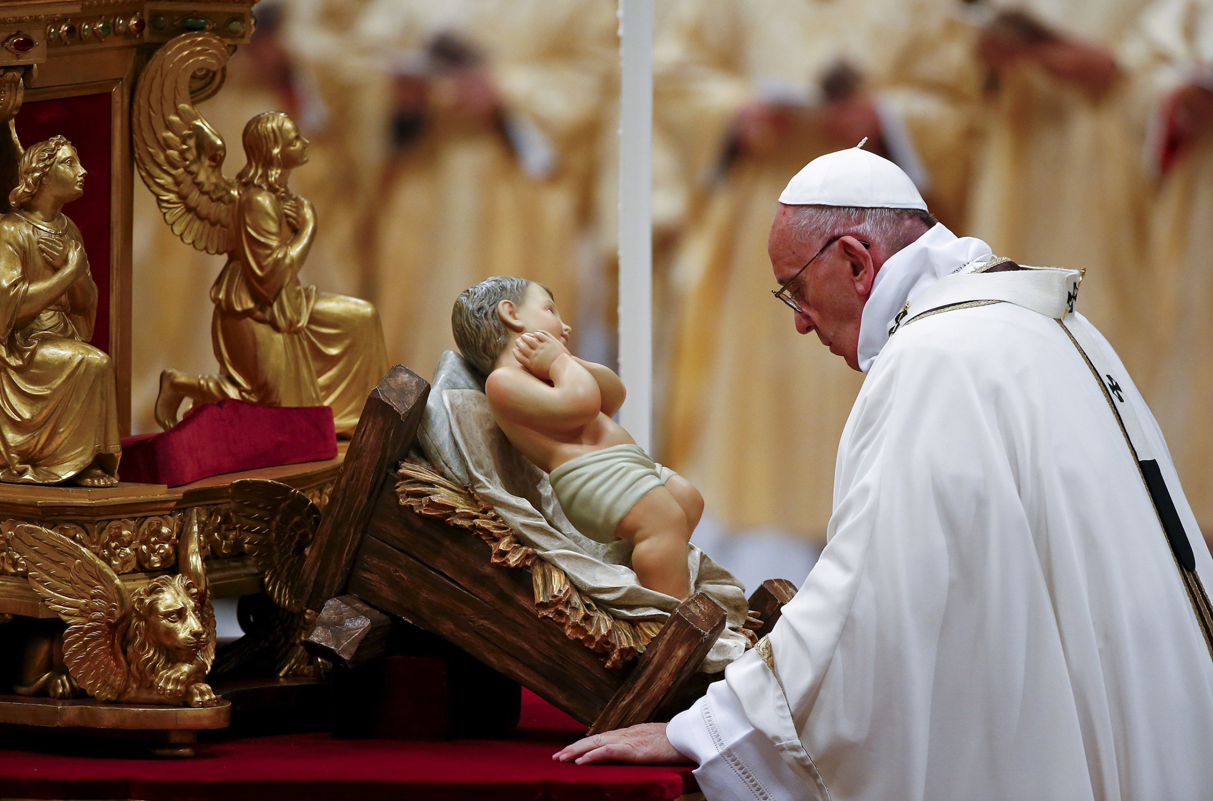 Pope Francis prays in front of a statue of baby Jesus as he leads the Christmas night Mass in Saint Peter's Basilica at the Vatican
