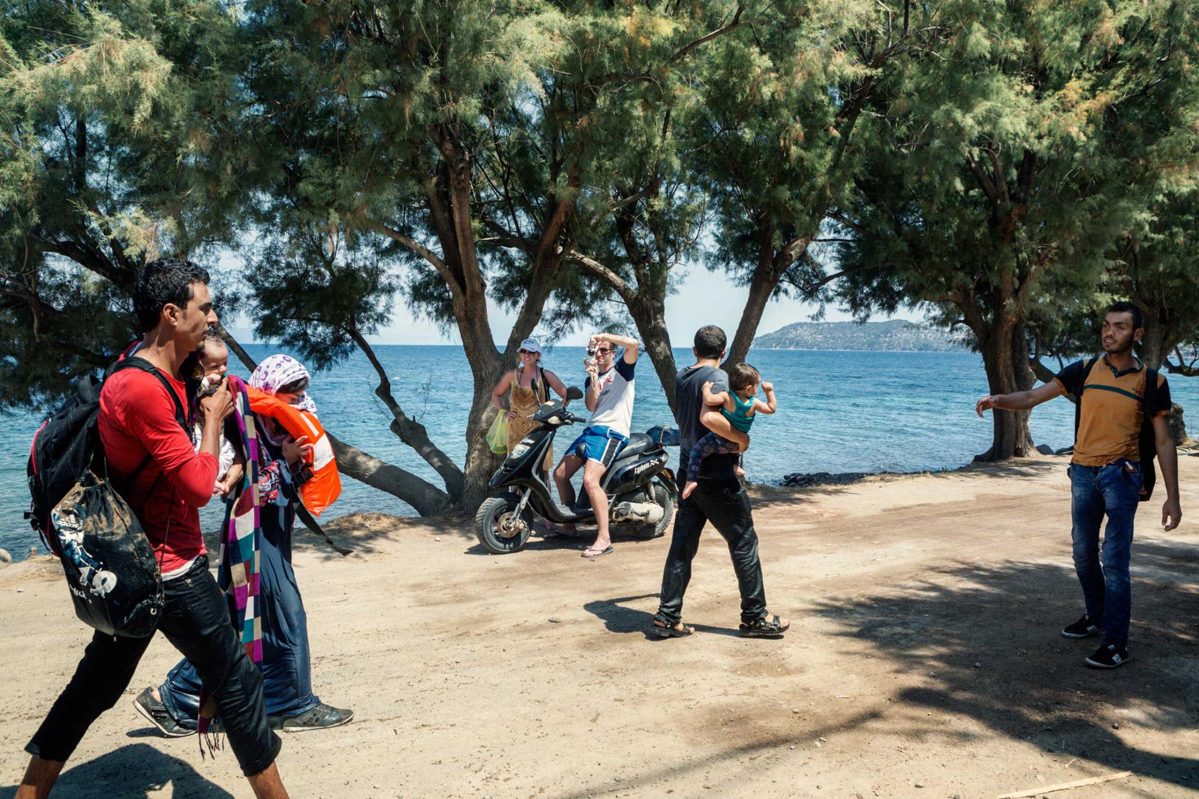 Two tourists photographed a Syrian family who arrived at Eftalou, on the northern coast of the Greek island of Lesbos, Greece, Aug. 12, 2015.
