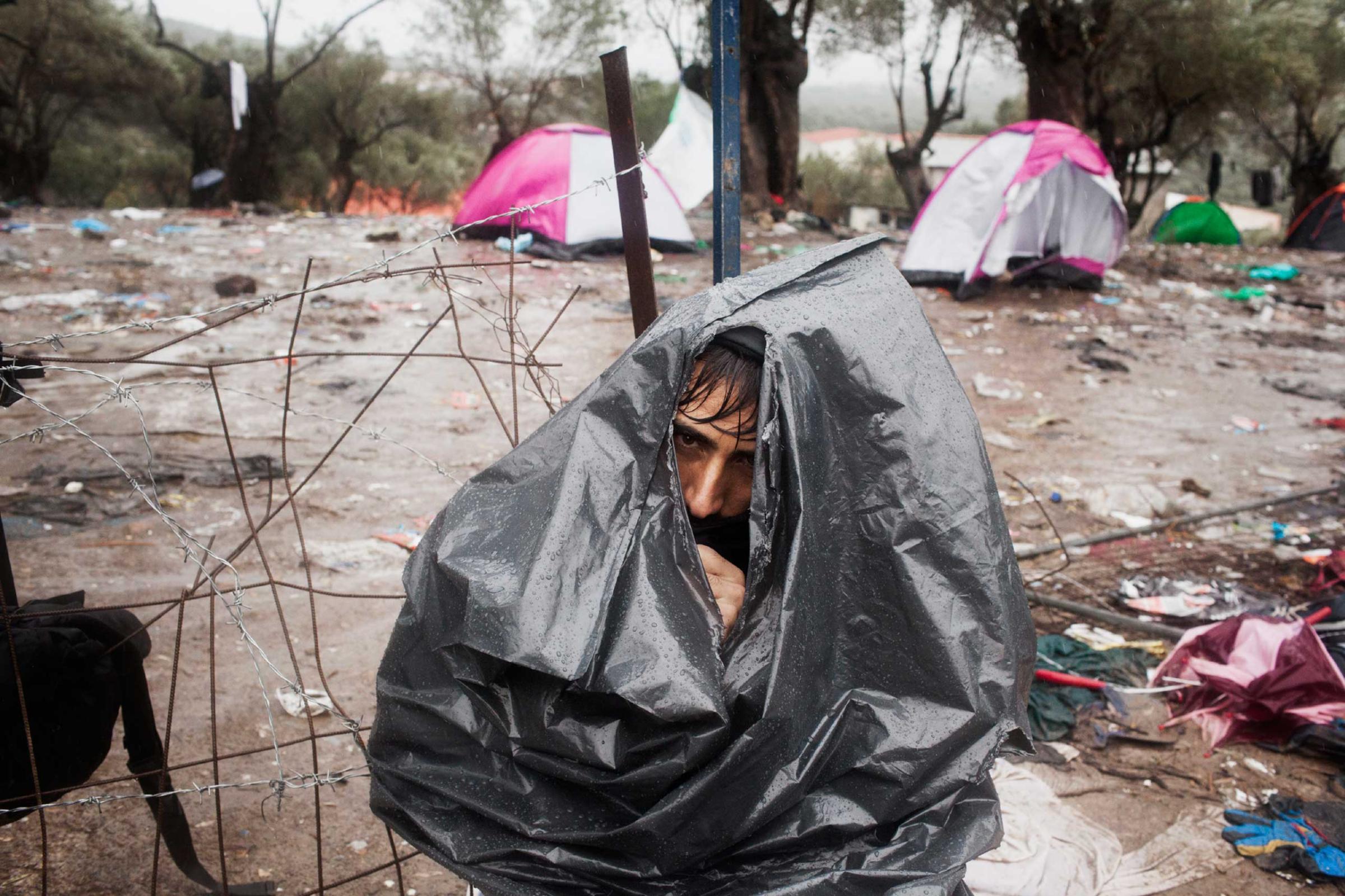 An Afghan refugee covered in a garbage bag at the Moria registration camp while he is waiting for his documents, Oct. 14, 2015.