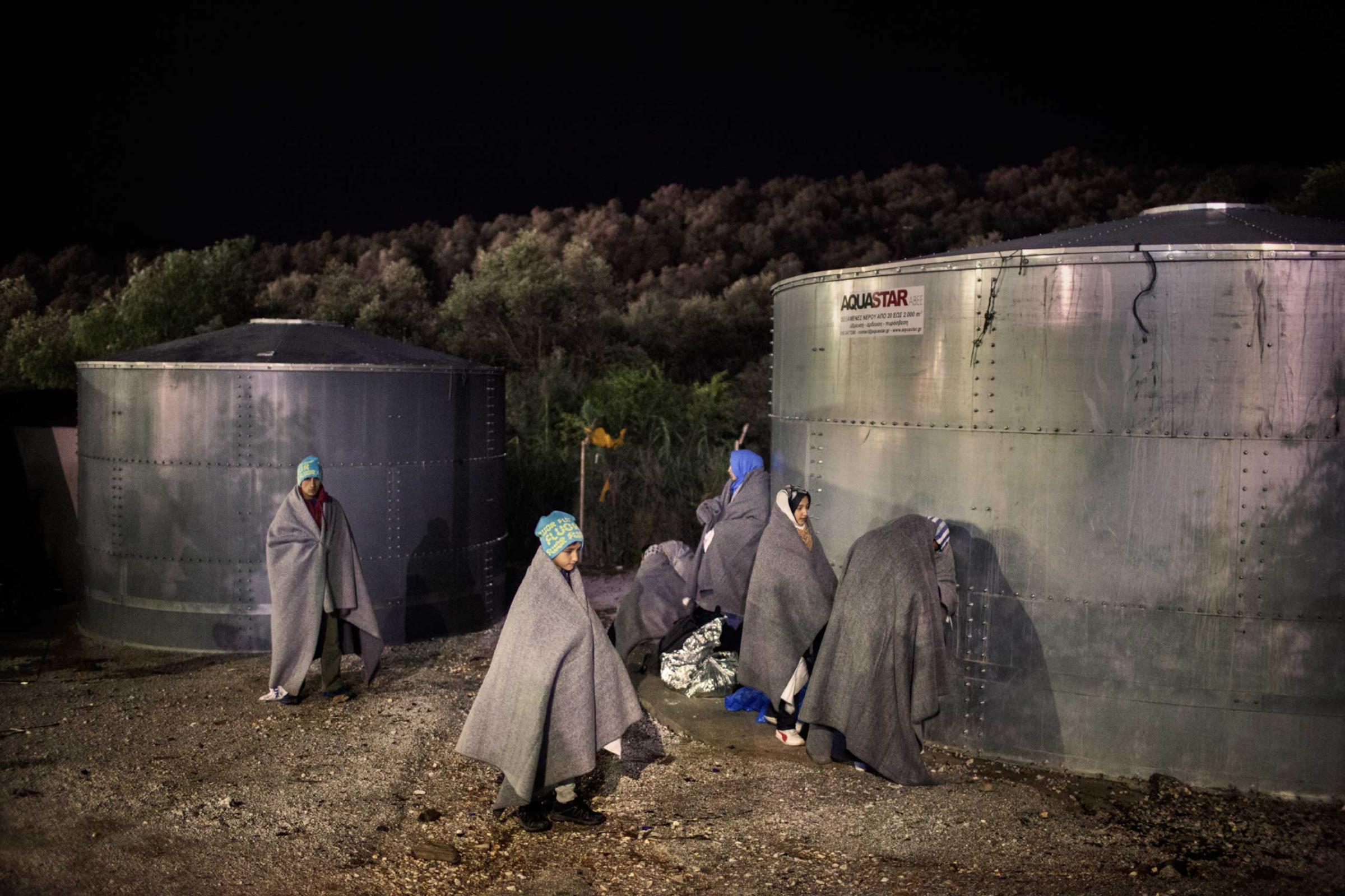 An Afghan family wait to be registered at the Moria camp in Lesbos, Greece, during a rainstorm, Oct. 29, 2015.