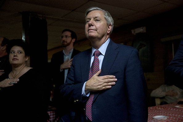 Senator Lindsey Graham, a Republican from South Carolina and 2016 presidential candidate, right, places his hand over his heart during the Pledge of Allegiance at the Stafford County GOP Christmas Party during a campaign stop at Newick's Lobster House in Dover, New Hampshire, U.S., on Friday, Dec. 18, 2015.