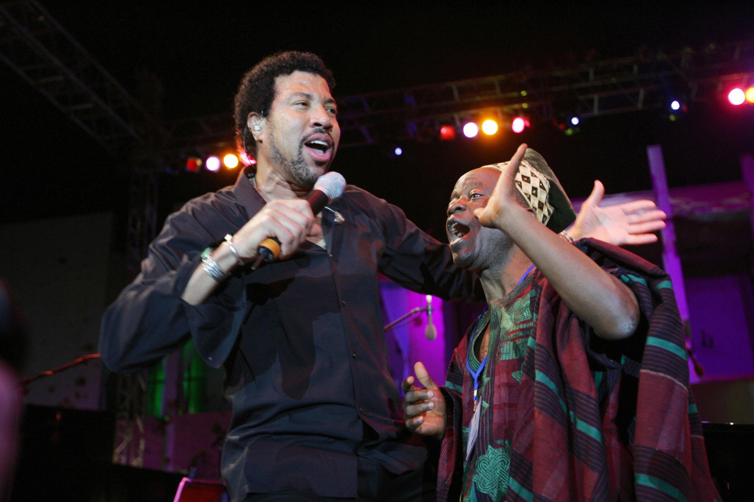 Lionel Richie performs with an unidentified Togolese man during a concert held in front of the house of Libyan leader Moamer Kadhafi in Tripoli on April 14, 2006.