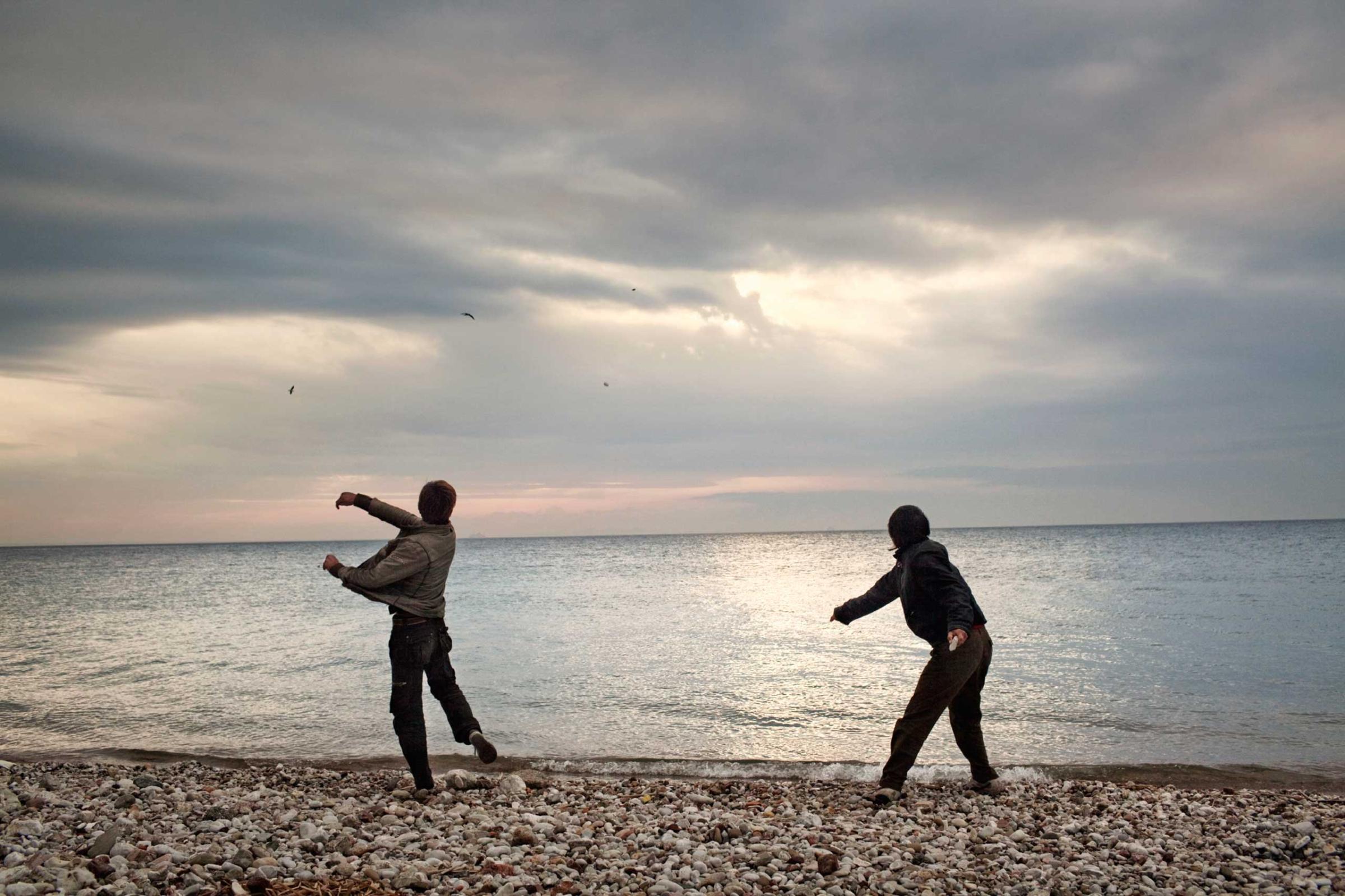 Afghan boys throw stones into the sea. At night, they will try to sneak into the port hoping to illegally board a ship bound for Italy, 2012.