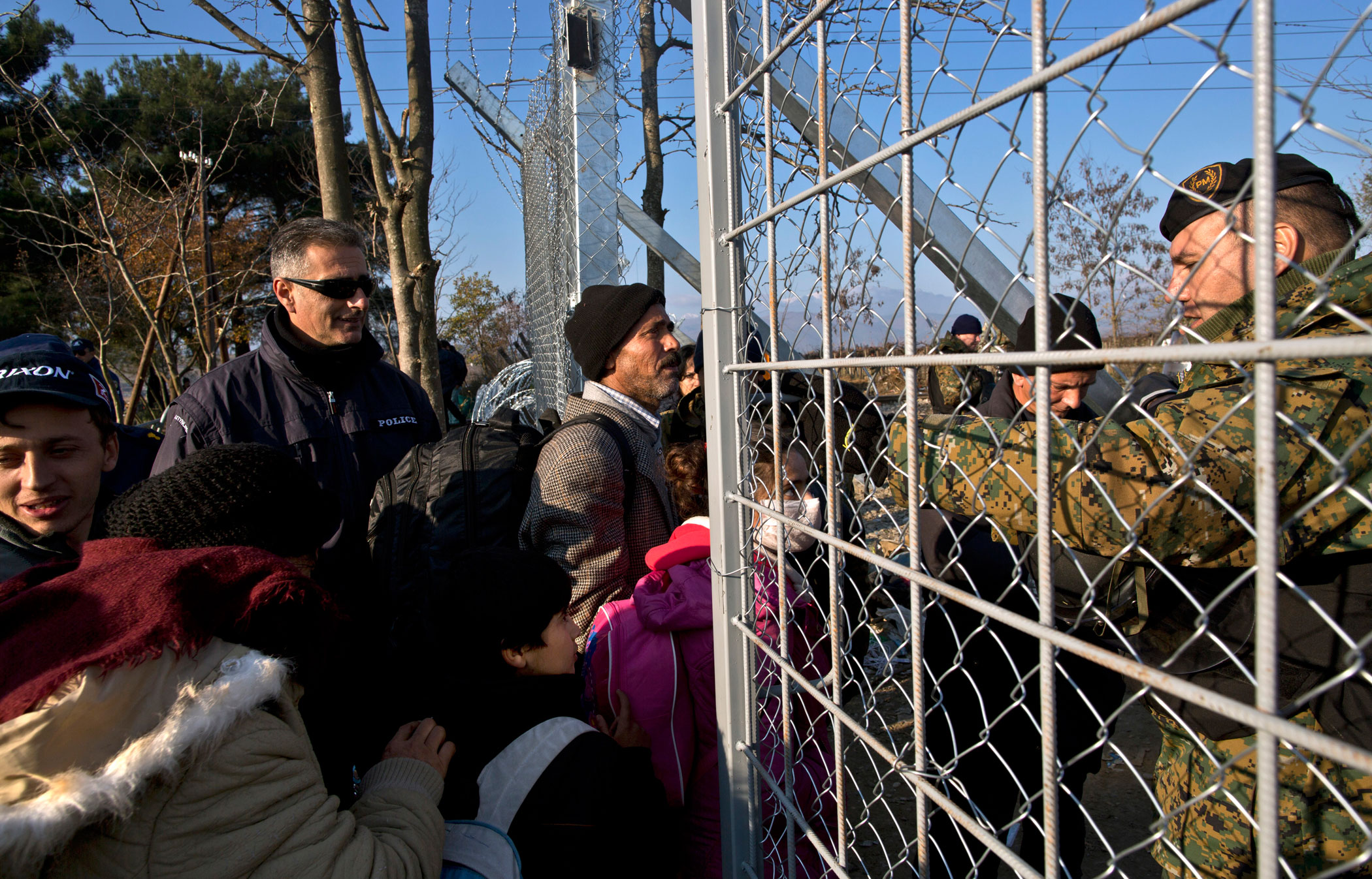 Qasu and his family approach Macedonian army officers as they cross a fence at the Greek-Macedonian border, near the northern Greek village of Idomeni, Dec. 5, 2015. The Qasus traveled via midnight ferry to Athens and then by bus to Greece's northern border.