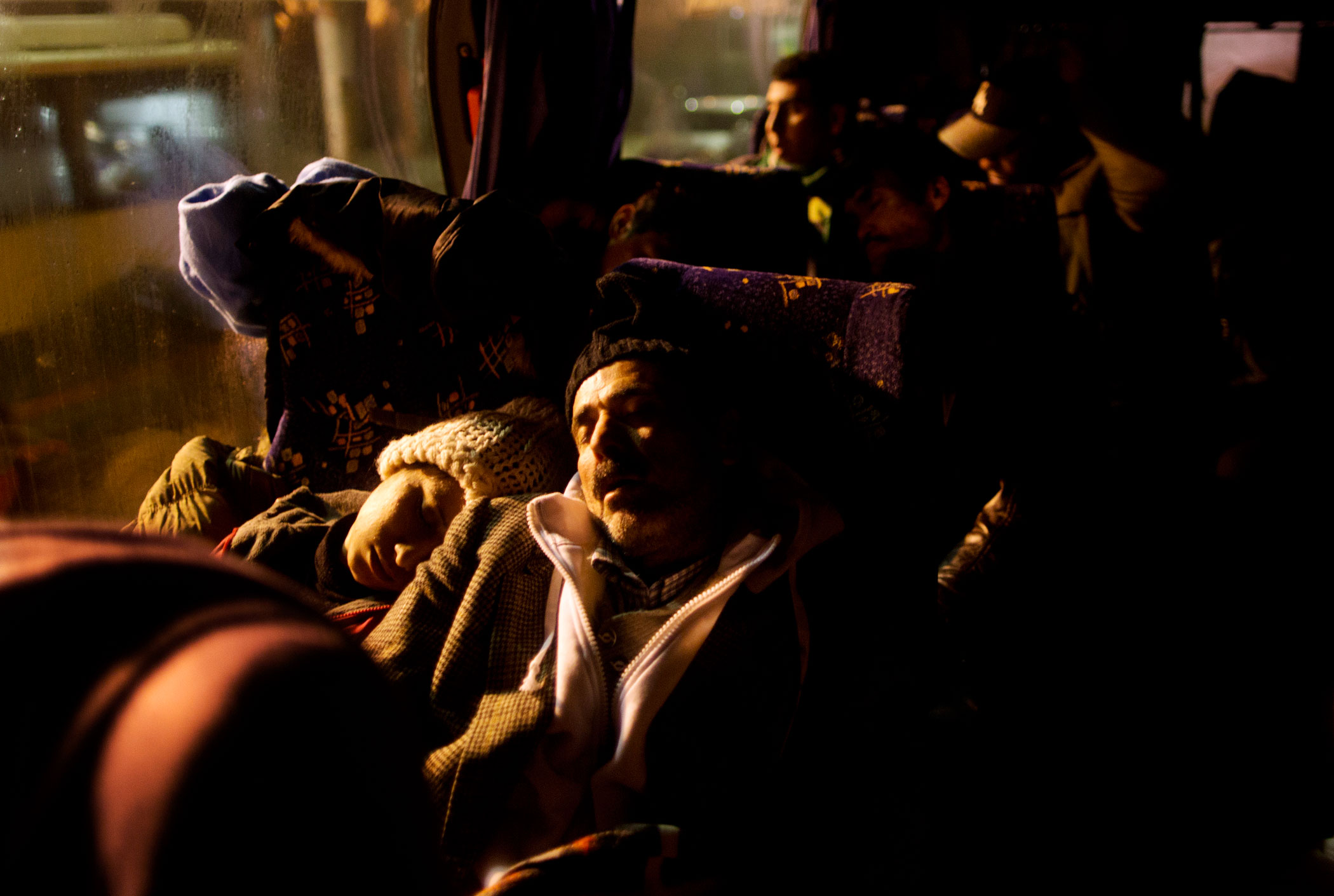 Delphine Qasu, 18, and her father sleep on a bus in Adasevci, Serbia, while waiting to be transported to the rail station where Serbian authorities load trains with refugees to Croatia, Dec. 6, 2015.