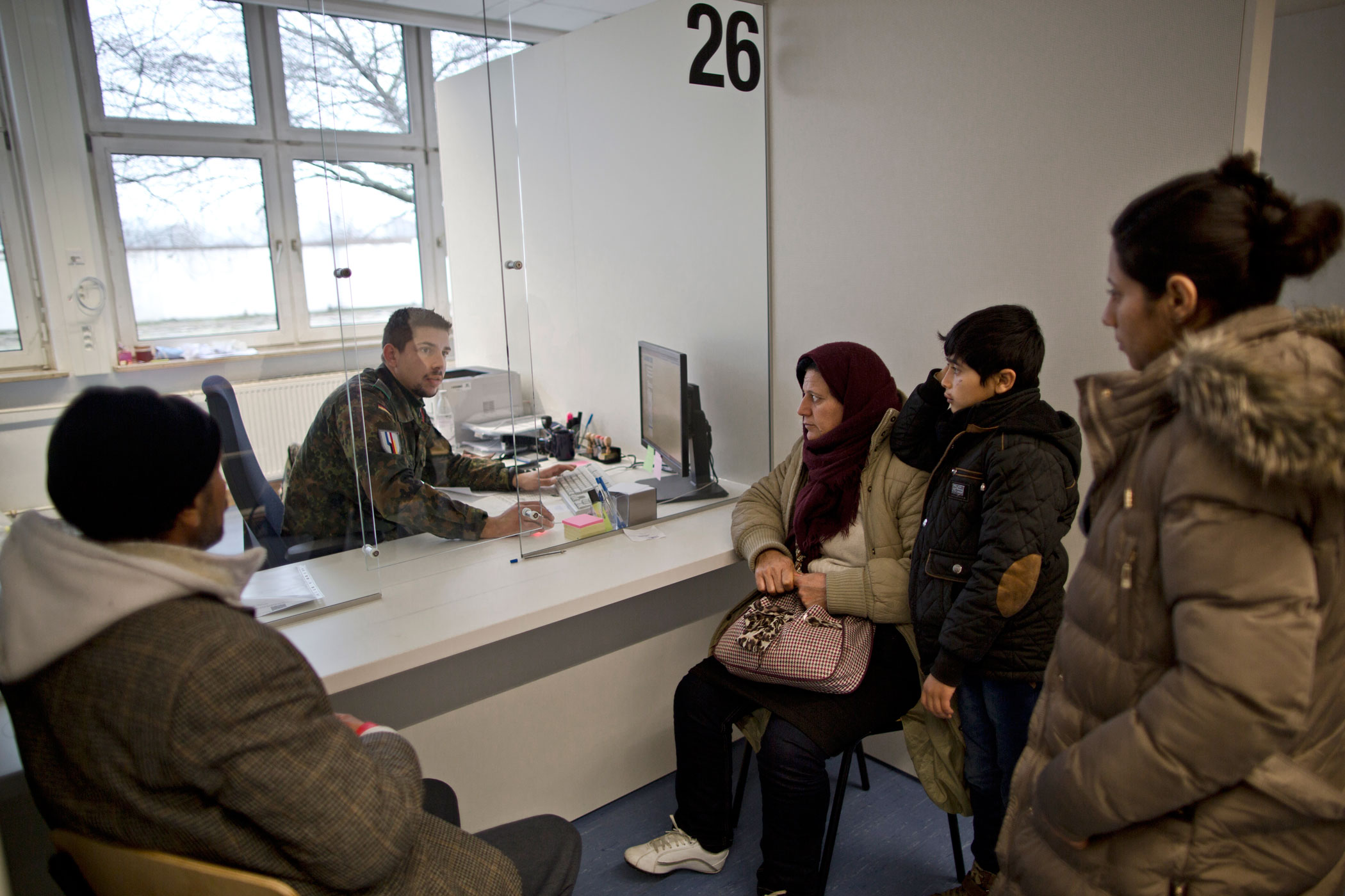 A German army soldier speaks with the Qasus as part of their asylum-seeking process at a registration center in Patrick Henry Village, Heidelberg, Germany, Dec. 9, 2015.