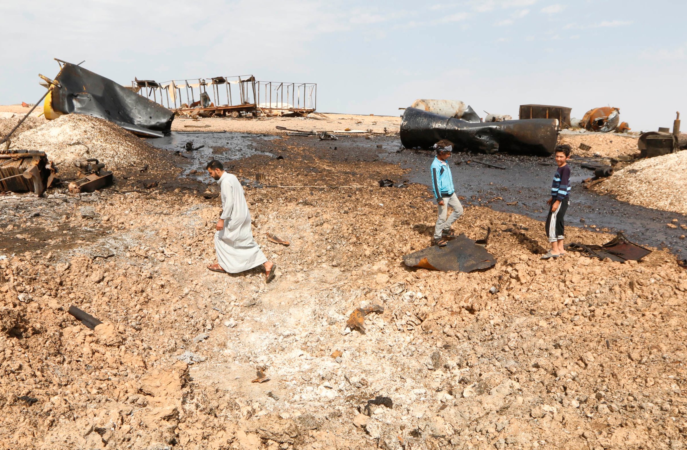 People inspect damage at an oil refinery that was targeted by what activists said were U.S.-led air strikes at al-Khaboura village, near the Syrian town of Tel Abyad of Raqqa governate