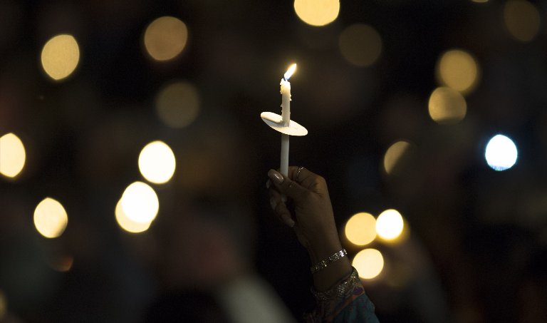 A mourner holds a candle as attending a vigil to pray for the victims of a mass shooting in San Bernardino, Calif. on Dec. 3, 2015.