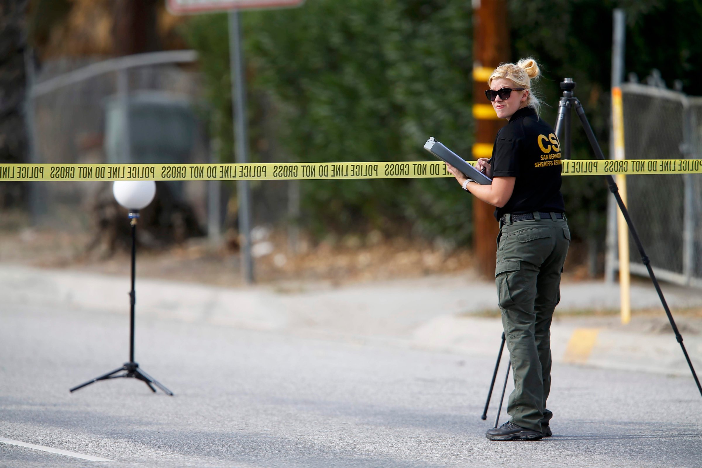 A Sheriff's Office Crime Scene Iinvestigator inspects the scene around an SUV where two suspects were shot by police following a mass shooting in San Bernardino