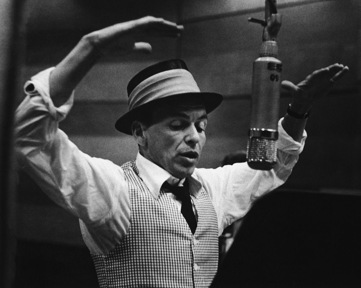 American singer and actor Frank Sinatra (1915 - 1998) gestures with his hands while singing into a microphone during a recording session in a studio at Capitol Records, early 1950s. (M. Garrett&mdash;Getty Images)