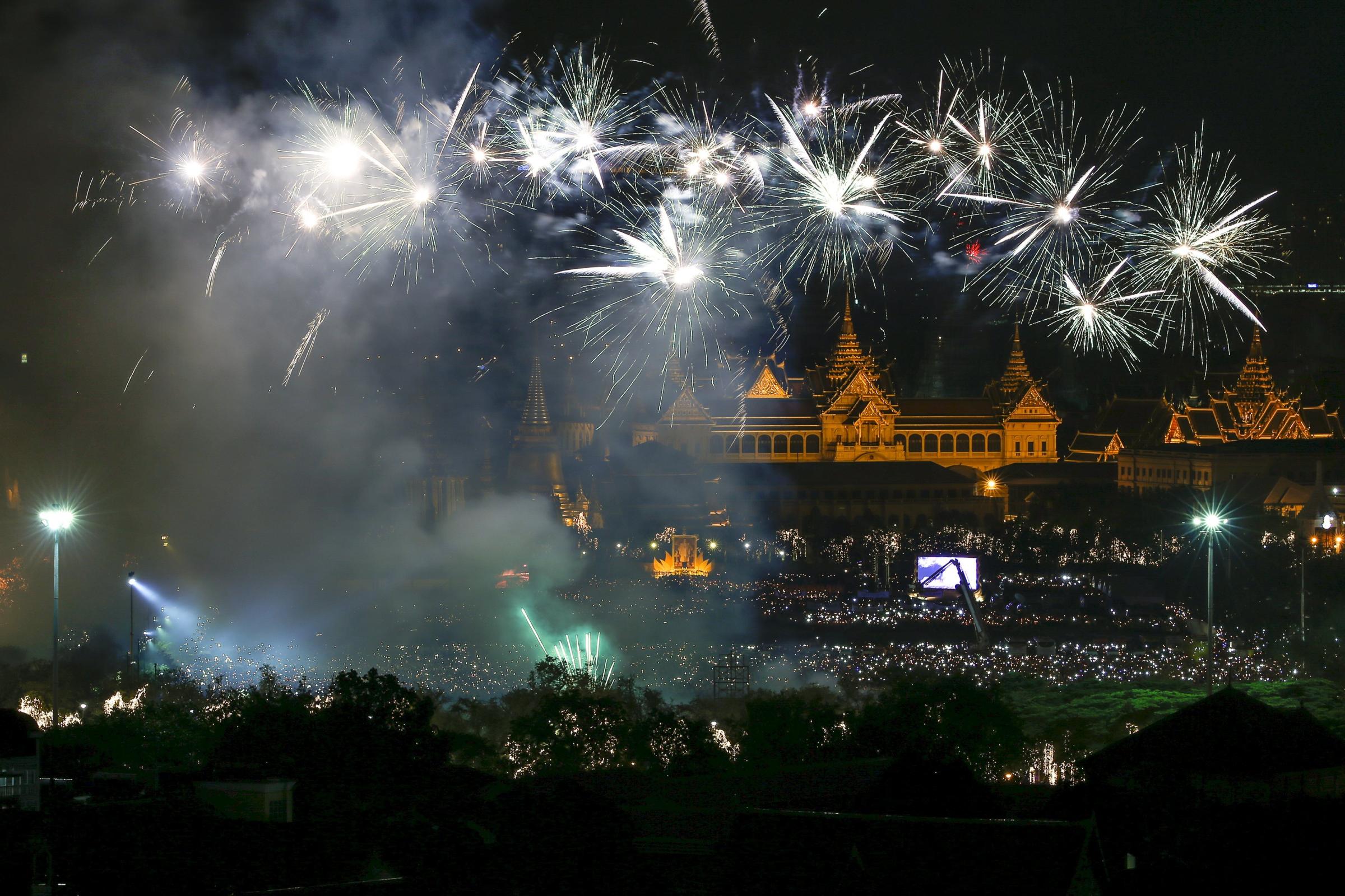 Fireworks over Grand Palace as people hold candles to mark birthday of Thailand's King Bhumibol Adulyadej to mark 88th birthday in Bangkok