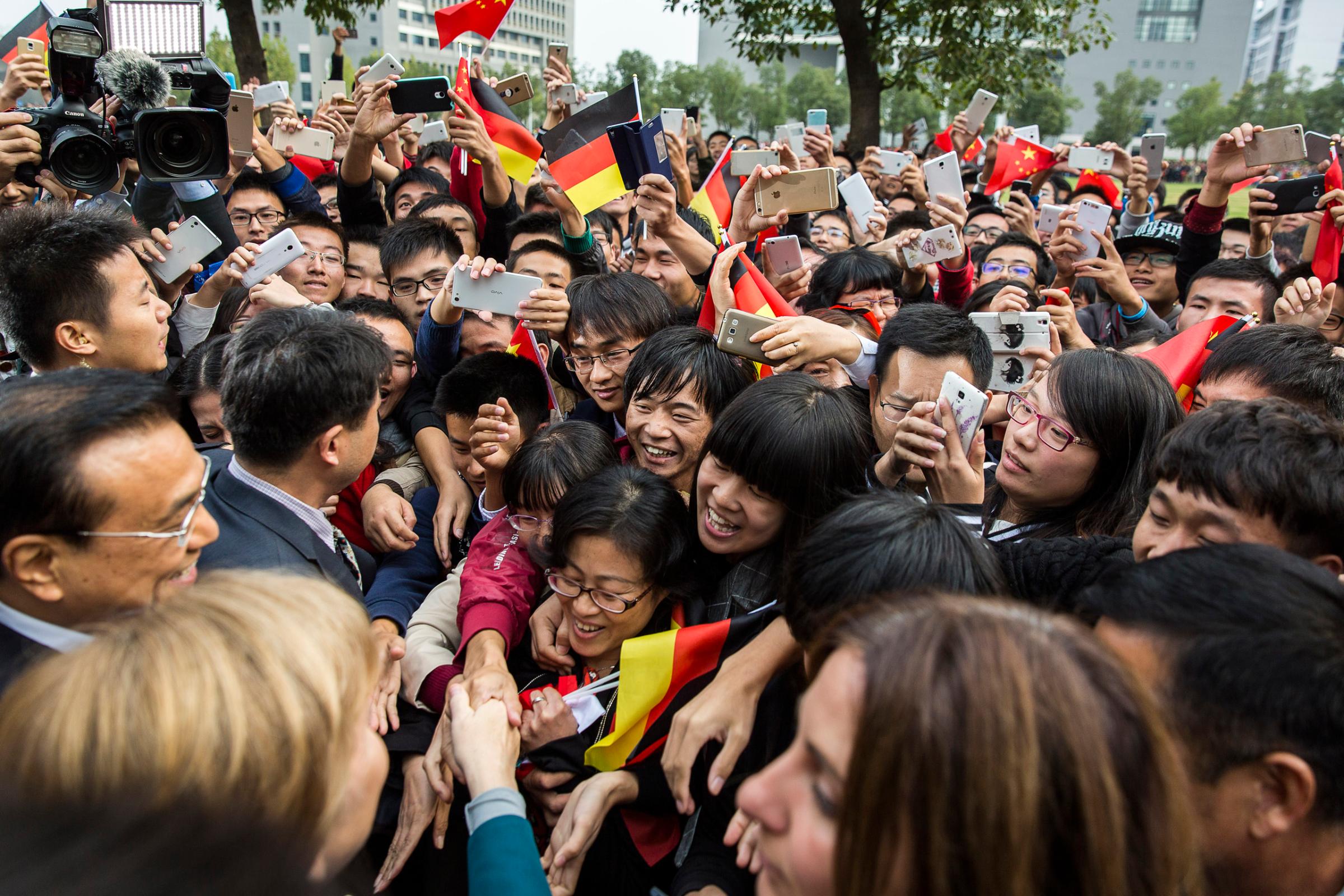 Chancellor Merkel and Chinese Premier Li Keqiang are being welcomed by students at Hefei University, China. Oct. 30, 2015.