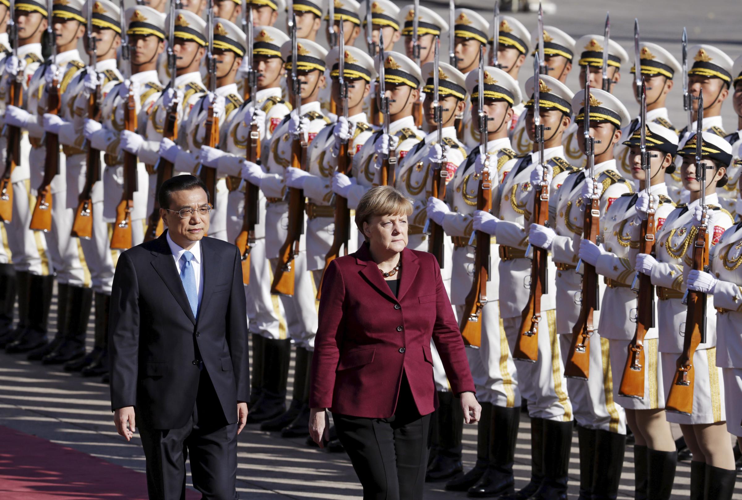 China's Premier Li Keqiang and Germany's Chancellor Angela Merkel inspect honor guards during a welcoming ceremony outside the Great Hall of the People in Beijing on Oct. 29, 2015.