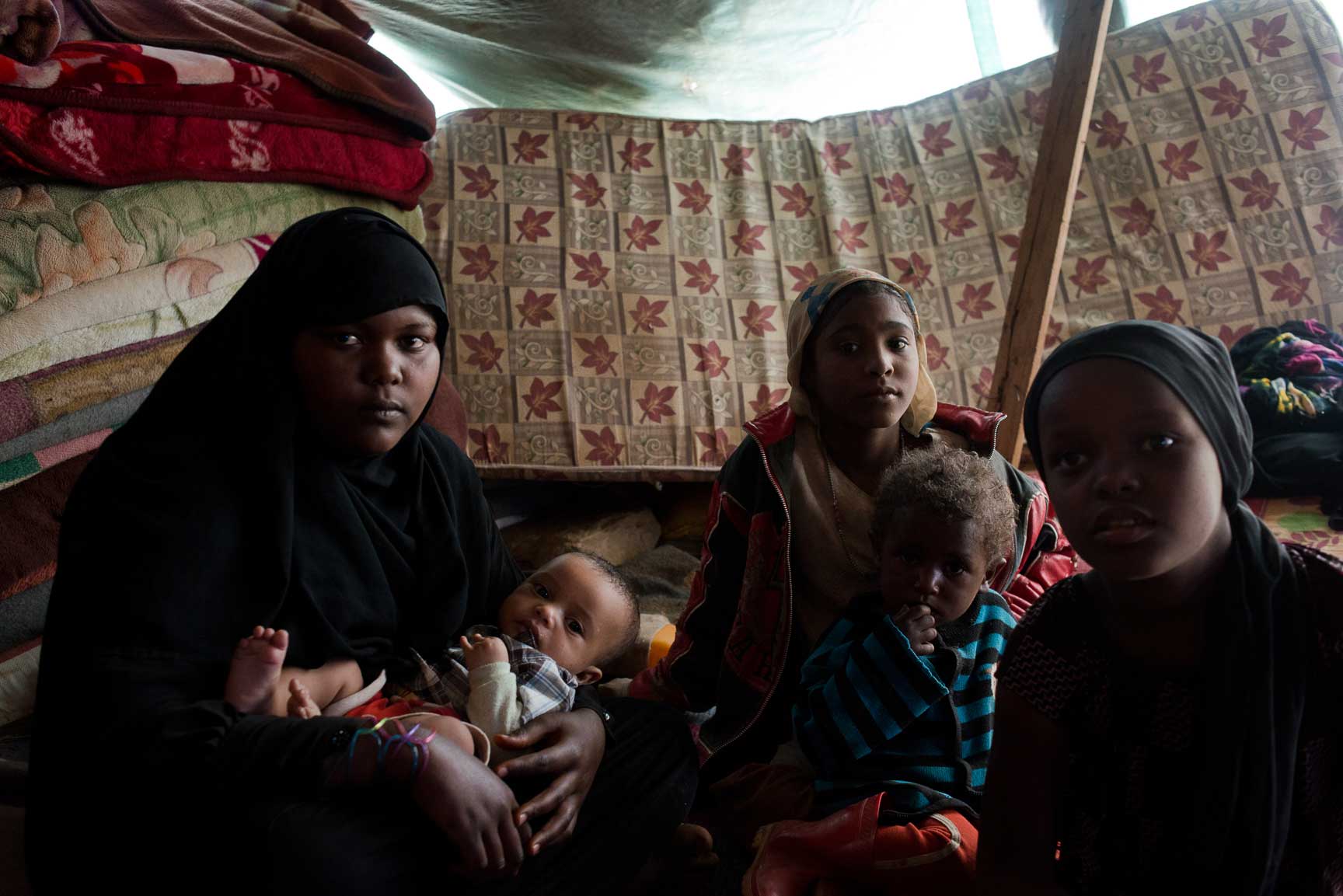 Children from a Yemeni family originally from the heavy-hit northern province of Sa'ada sit in their tent outside on July 7, 2015 in Amran, Yemen. They are members of Yemen's marginalized community, the Muhamashin, most of whom are not able to shelter in schools or family elsewhere.