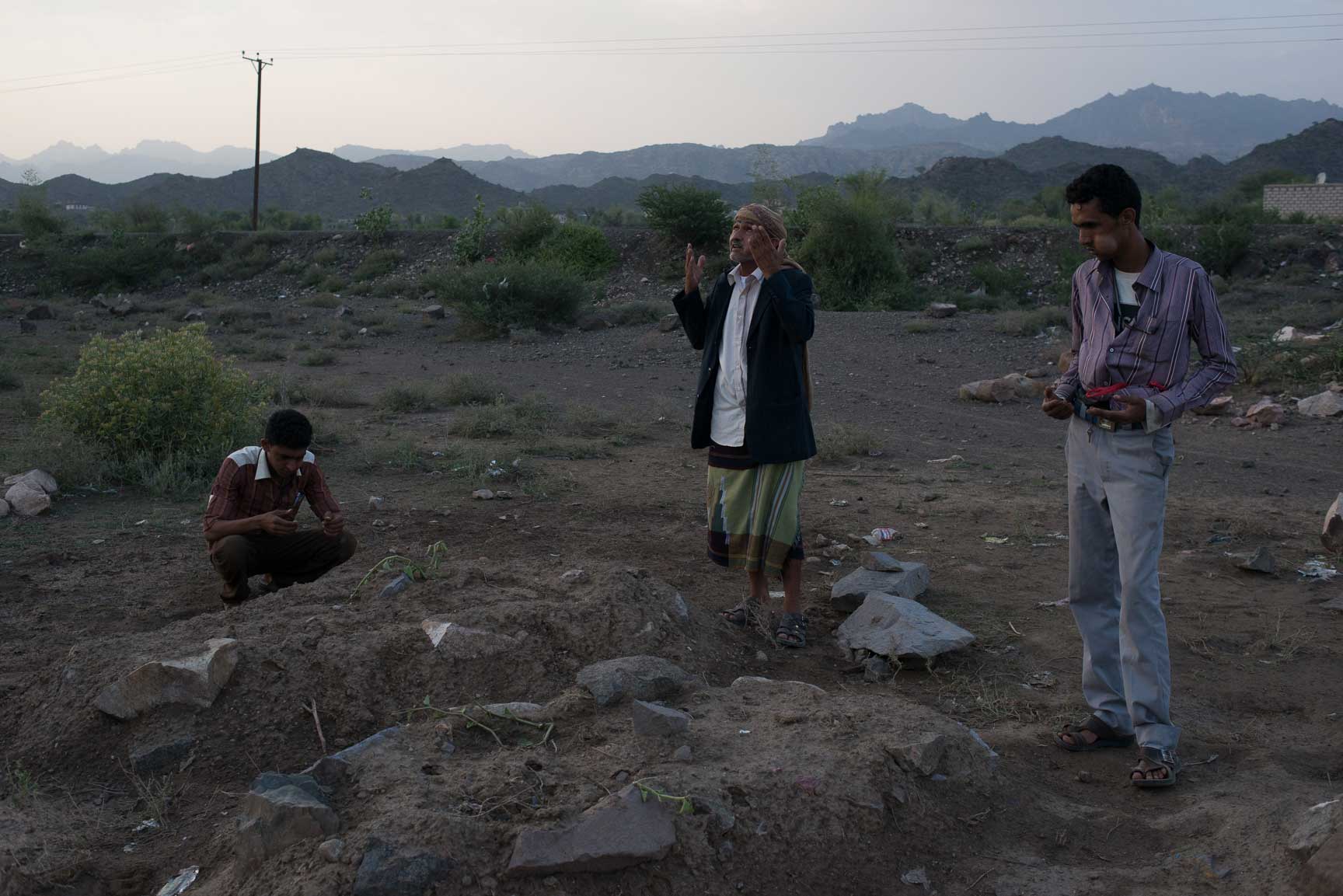 Muthana Abdullah Jaylani (center) prays over the graves of his relatives and neighbors who were killed by an airstrike, July 22, 2015. The strike killed at least five people, though only two were reported to the local MSF Hospital.