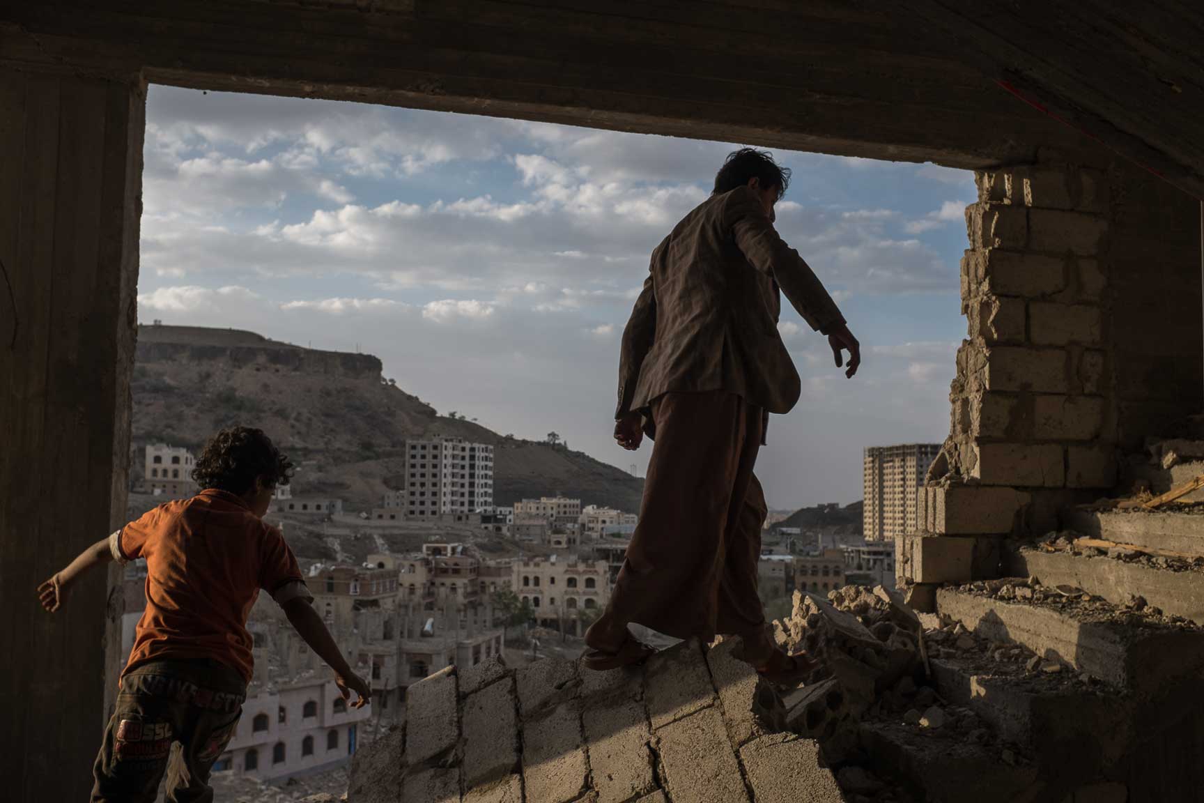 Yemeni brothers climb the remains of an apartment building in Faj Attan, a district in Yemen heavily targeted by airstrike, Monday Auugst 17, 2015 in Sana'a, Yemen.