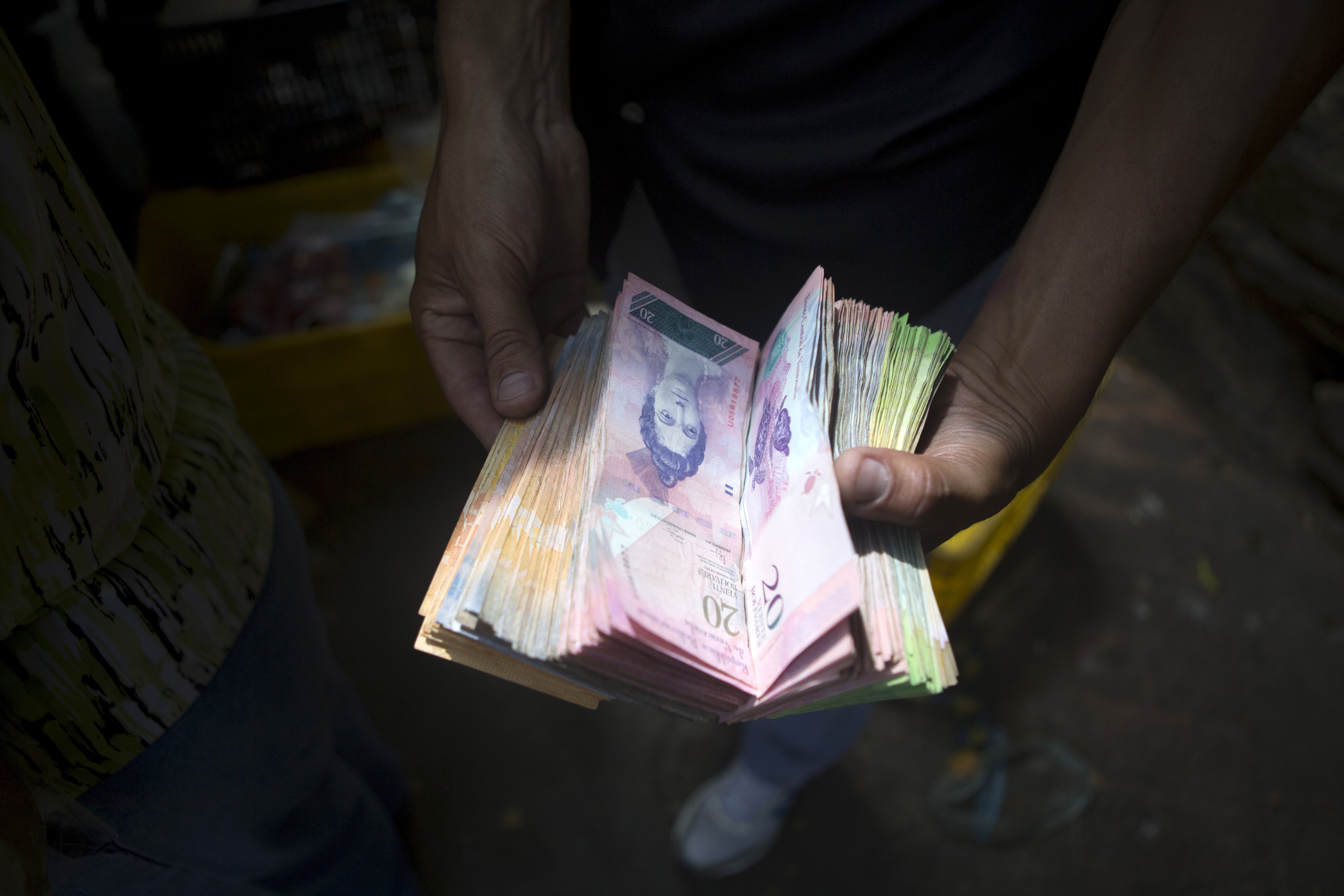A man displays bolivar notes that he carries to pay for goods at a street market in Caracas